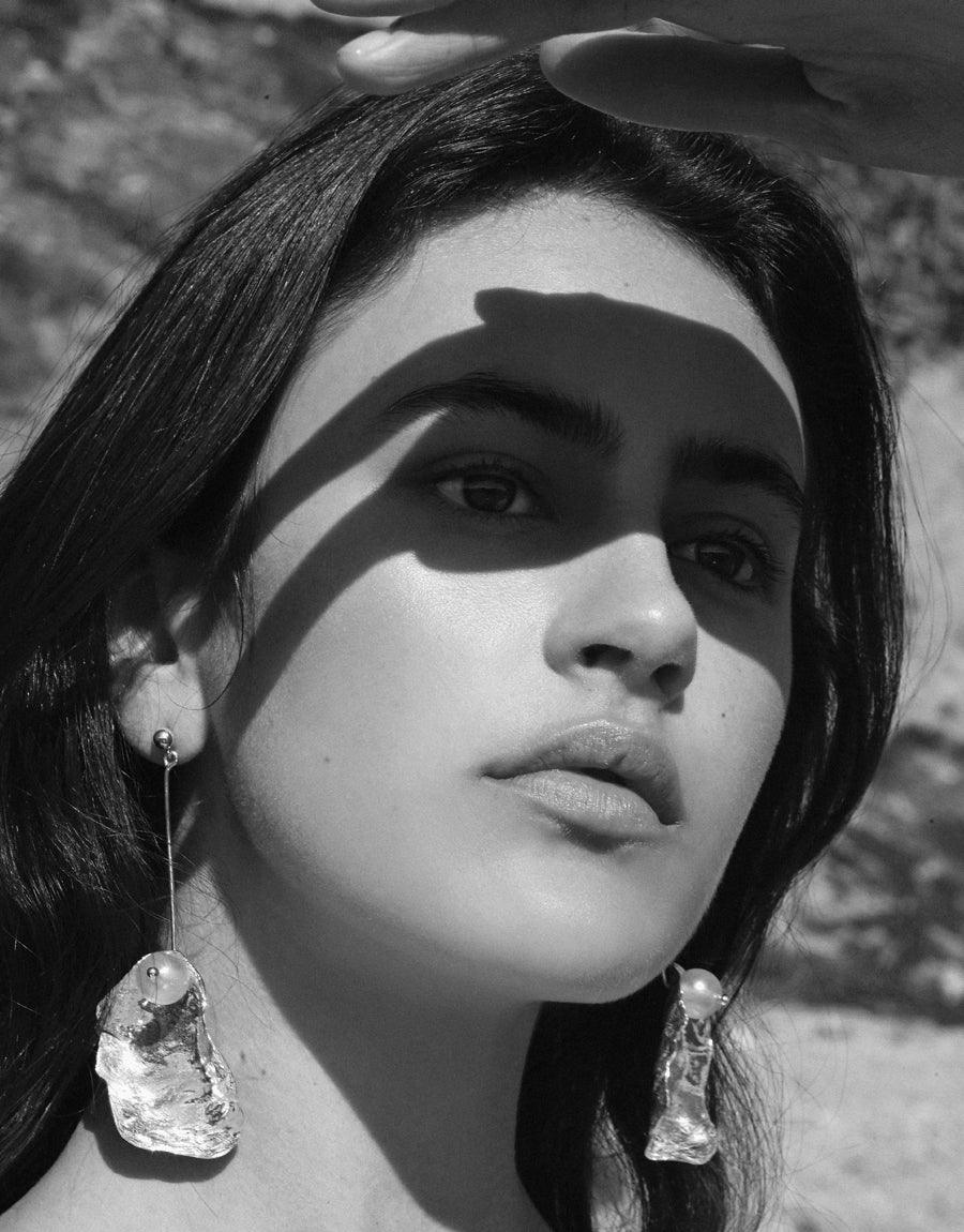 Monochrome portrait showcasing "Not A Pearl Earring" - sustainable dangle earrings with Eco Gem pearls made from recycled glass, hanging from orb posts. Striking shadows accentuate the model's features and the earrings' unique design. Handcrafted by CLED.