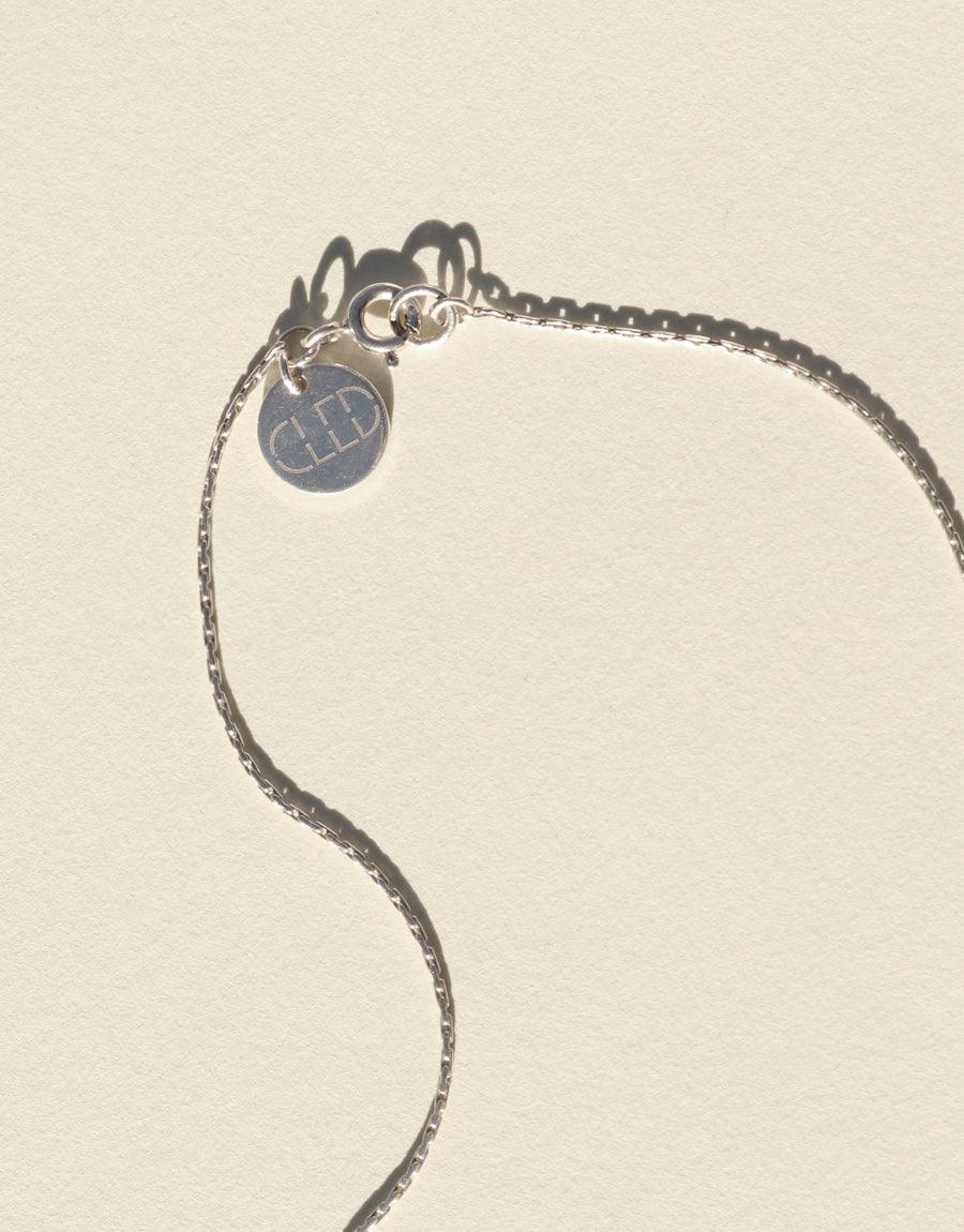 Elegant sterling silver chain necklace with a delicate curve, featuring a small circular pendant with the CLED logo. Minimalist design perfect for everyday wear. Showcasing the Minimal Ball Necklace by CLED.