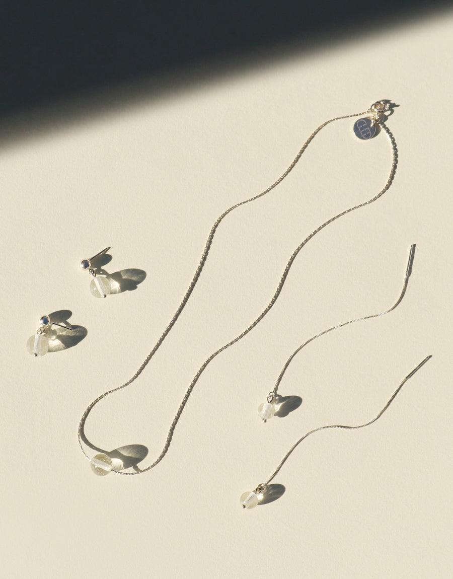 Minimal Line Earrings featuring delicate silver chains with suspended clear glass pendants. Eco-friendly jewelry set on a cream background with soft shadows. Elegant, sustainable design for everyday wear. CLED