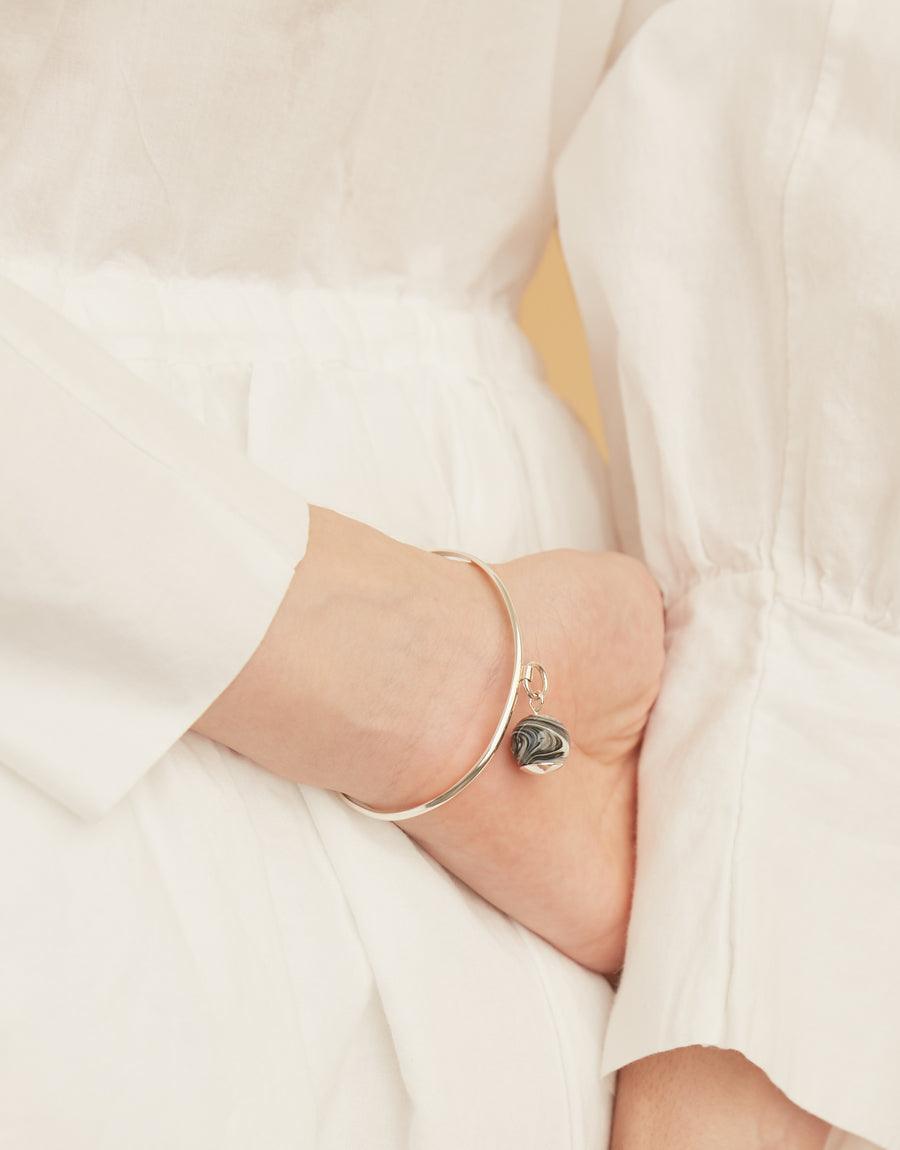 Elegant Drop Bracelet featuring a sterling silver cuff with a unique marble glass gem pendant, showcasing minimalist design and sustainable craftsmanship. Handmade in Los Angeles, this CLED piece combines classic style with eco-conscious luxury.