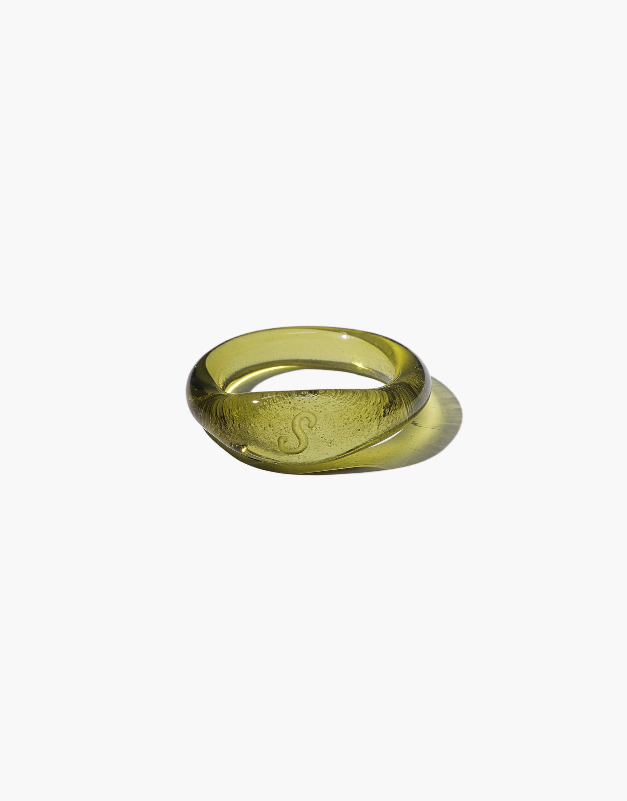 Engravable Signet Ring made from eco-friendly repurposed glass in a translucent olive green color, featuring a smooth rounded band with an etched letter 'S' on the face, showcasing sustainable craftsmanship and personalized design by CLED
