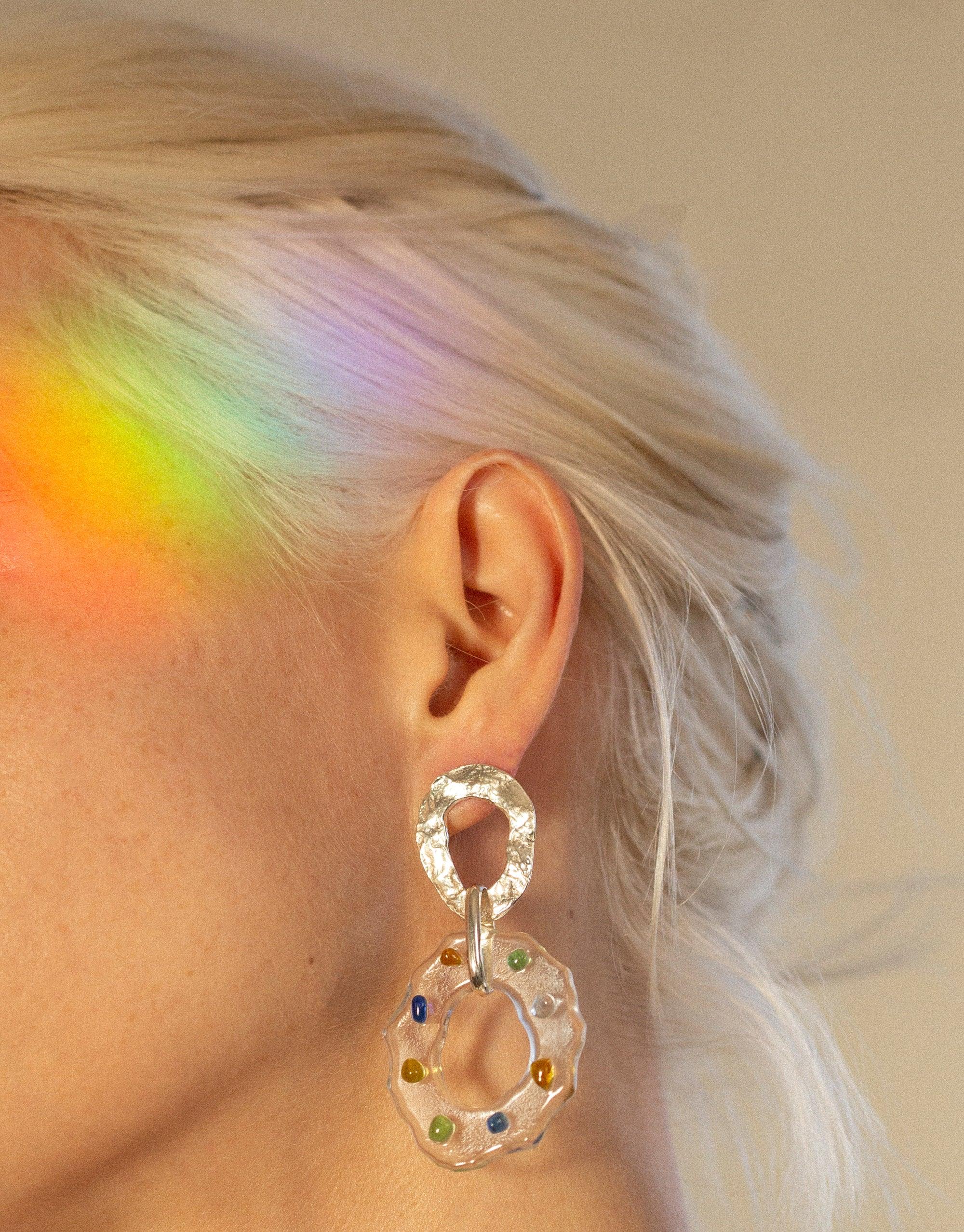 Elegant High Tide Earrings in Spectrum with colorful eco gems, showcasing prismatic effect on model's ear. Rainbow light reflection on blonde hair. Handcrafted sustainable jewelry by CLED.