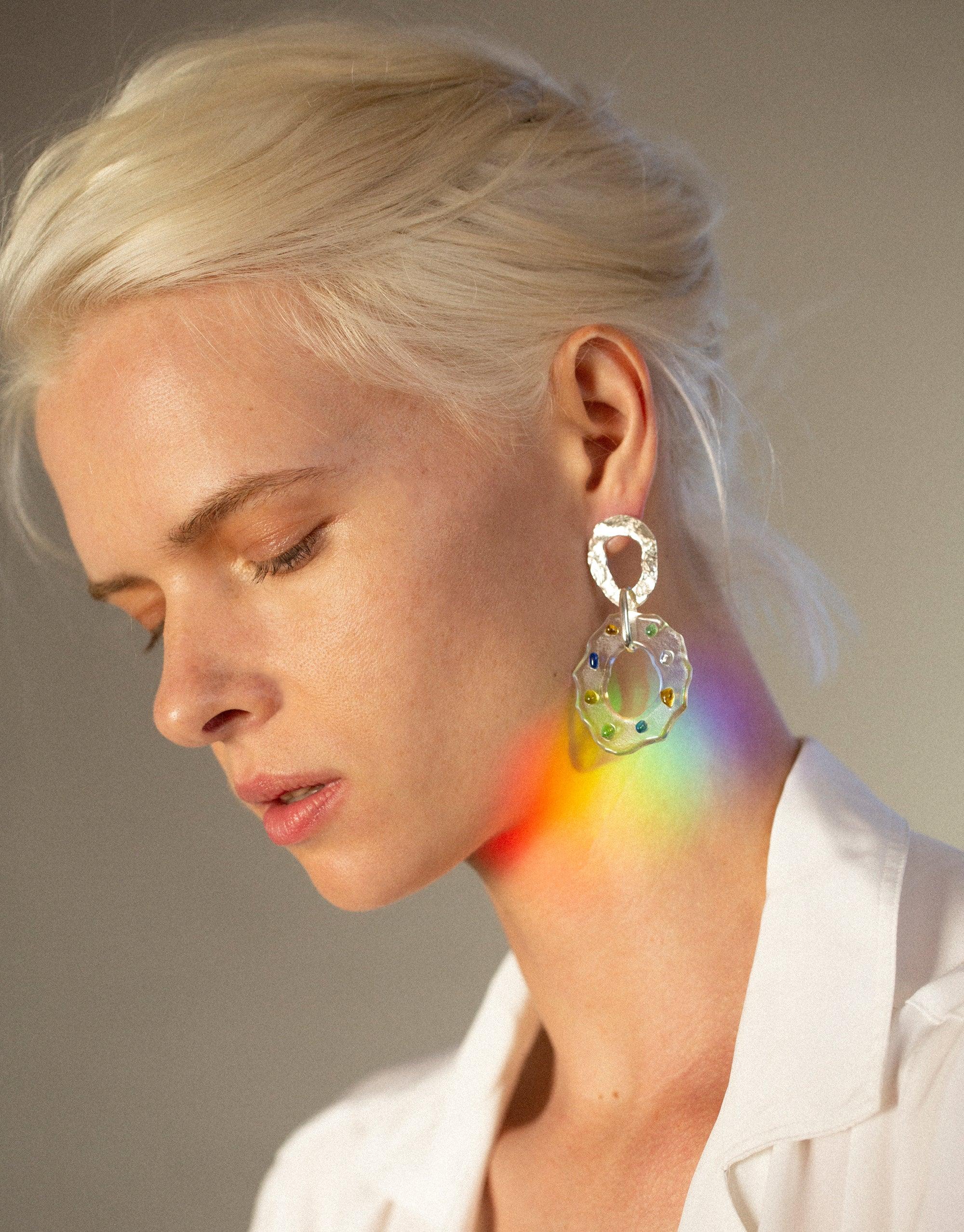 Elegant dangle earrings with prismatic effect, showcasing eco-friendly glass design. Rainbow colors reflect on model's neck, highlighting the unique spectral properties of High Tide Earrings in Spectrum. Sustainable jewelry handcrafted from upcycled materials by CLED.