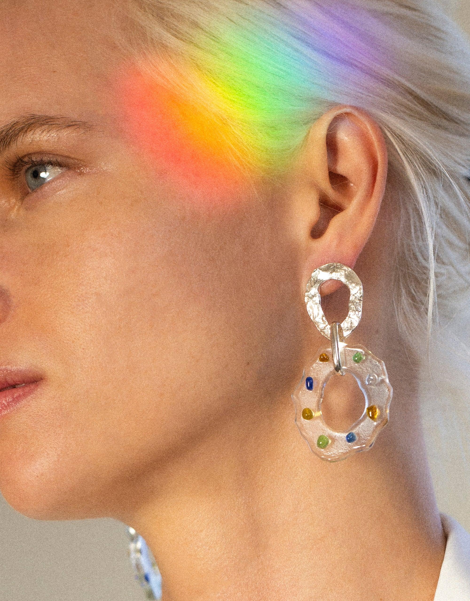 Colorful spectrum light on model wearing High Tide Earrings in Spectrum, featuring handcrafted eco gem circular design with multi-colored accents, showcasing sustainable jewelry artistry by CLED