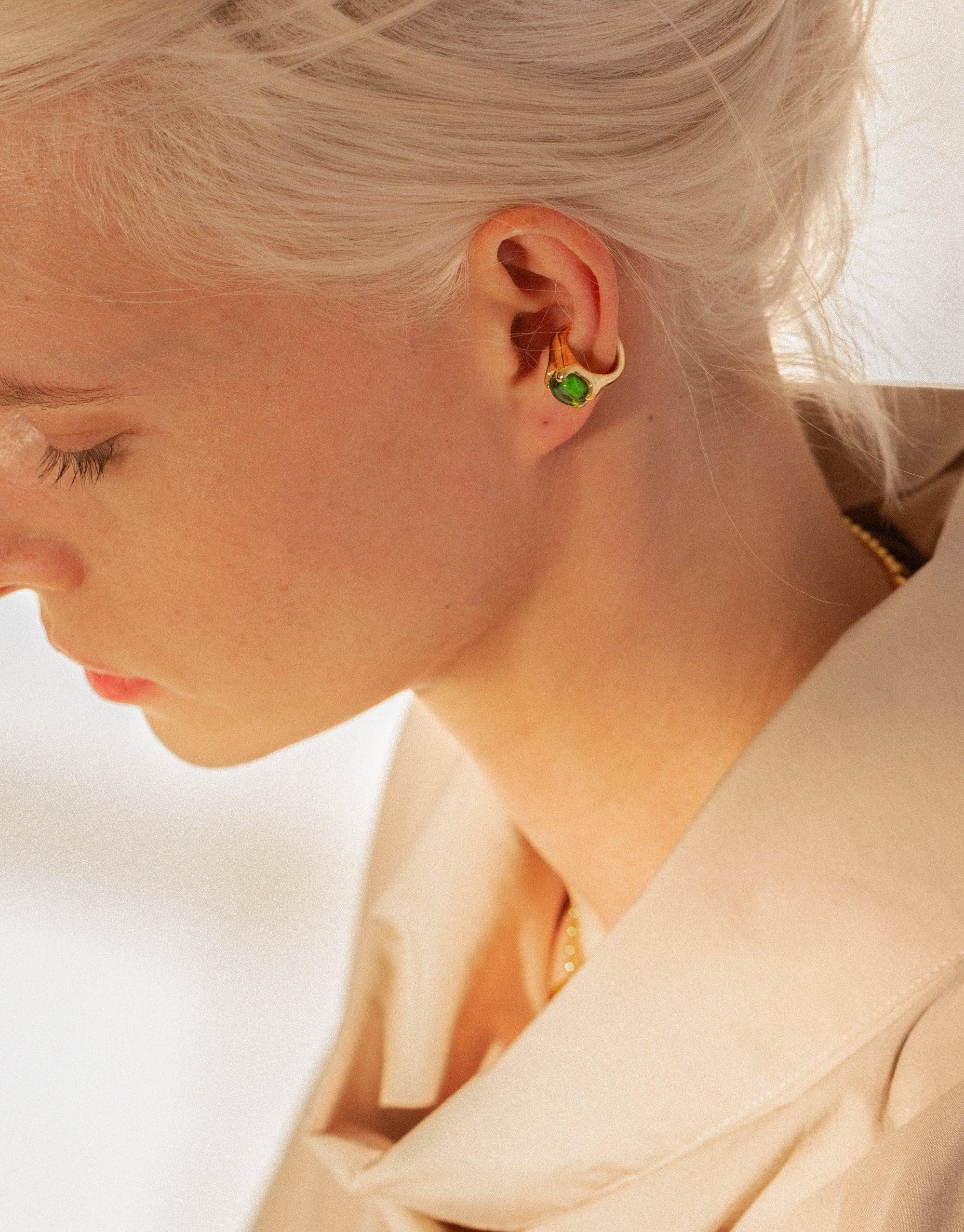 Close-up of a person wearing the Beam Ear Cuff, featuring a vibrant green eco gem repurposed from discarded glass. The ear cuff elegantly adorns the earlobe, showcasing sustainable jewelry design by CLED.