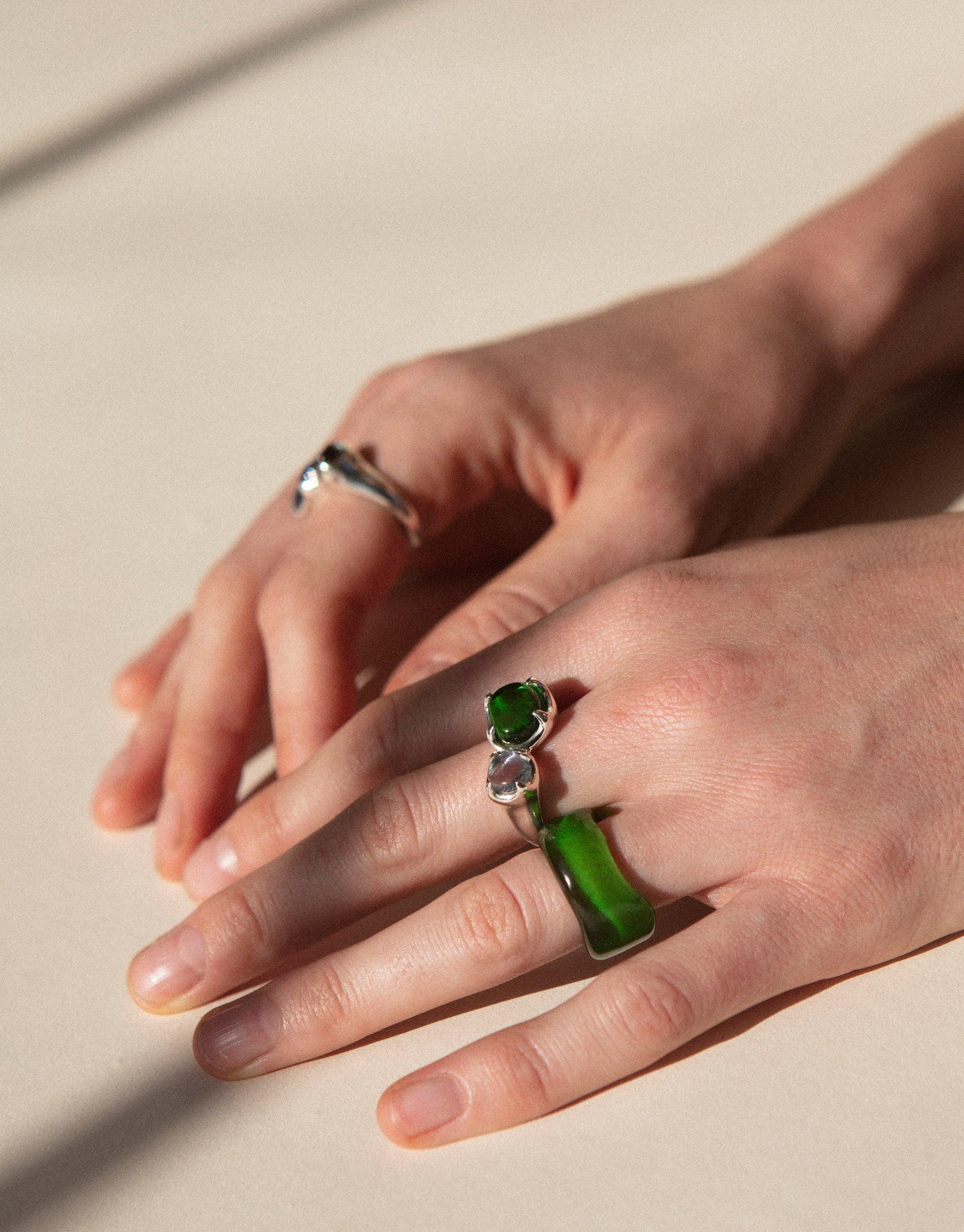 Duo Beam Ring featuring vibrant green eco gems on elegant silver bands, showcasing sustainable jewelry design. Hands modeling unique rings made from upcycled glass, reflecting light like a prism. Handcrafted in Los Angeles by CLED.