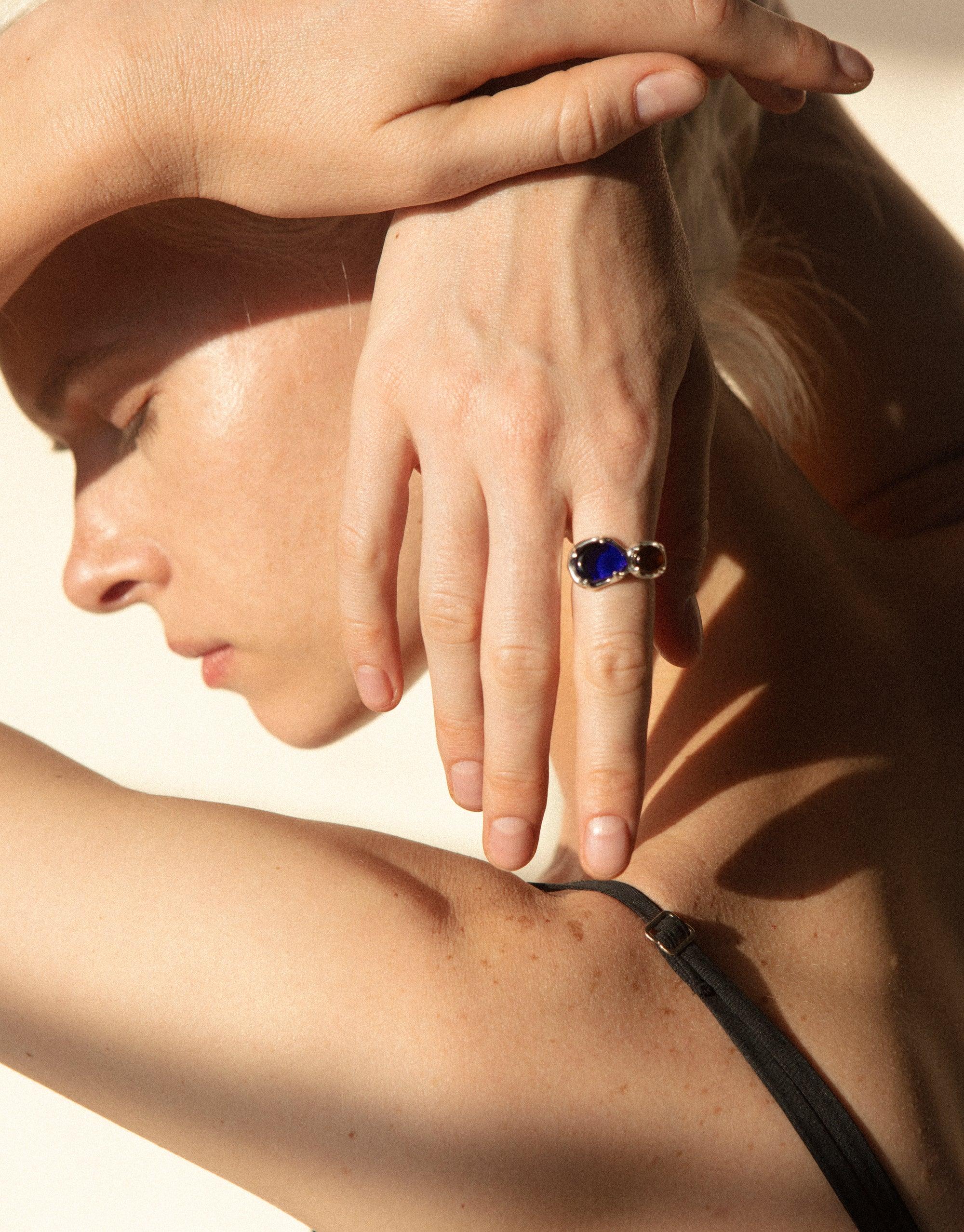 Hand with Duo Beam Ring featuring vibrant blue eco gem, showcasing prism-like colors in sunlight. Elegant and sustainable jewelry design by CLED.