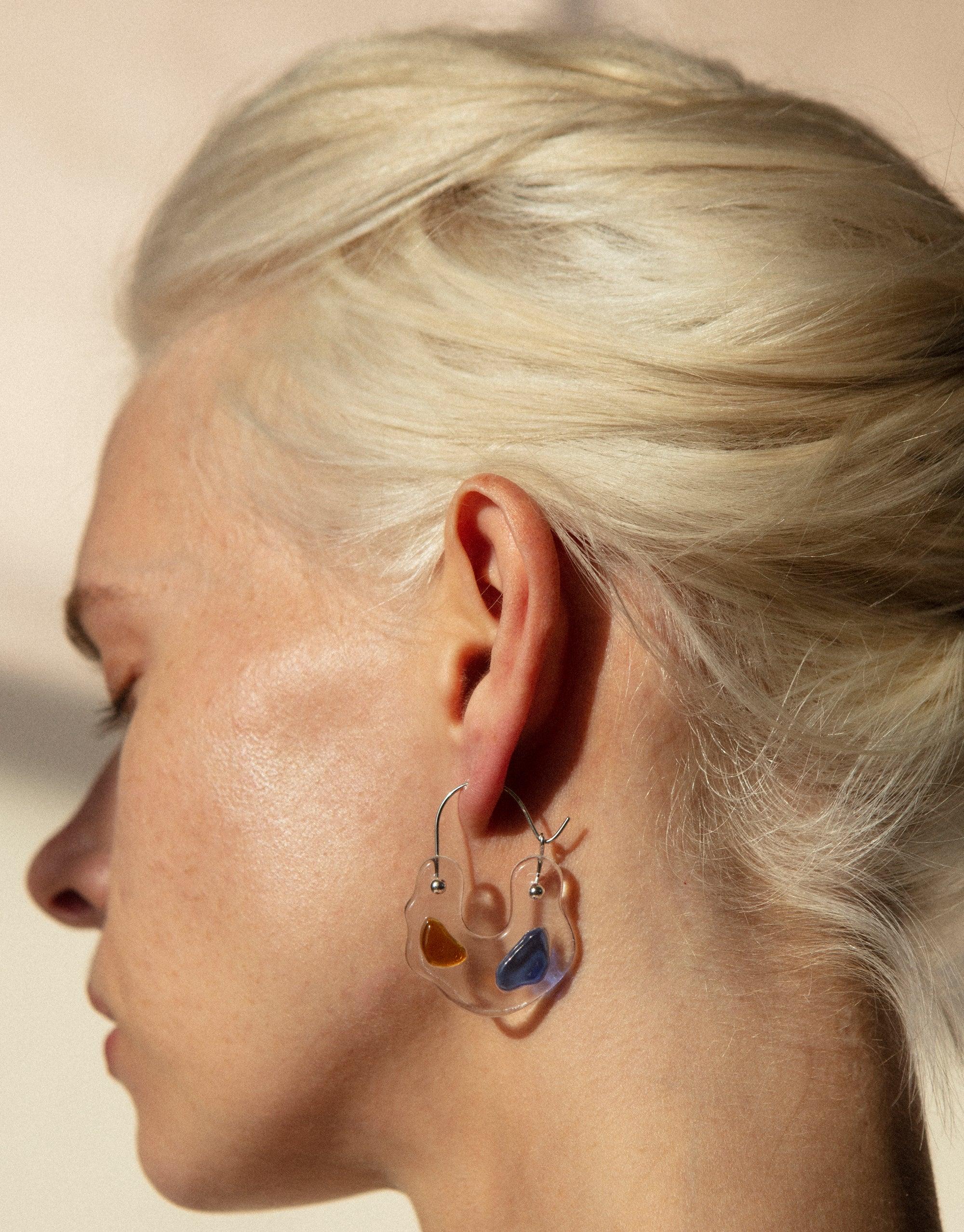 Close-up side view of an ear wearing Ray Hoop Earrings, featuring colorful eco gems in prism-like shapes. The earrings showcase sustainable jewelry design with upcycled glass, embodying the spectral colors of light. Ray Hoop Earrings by CLED.