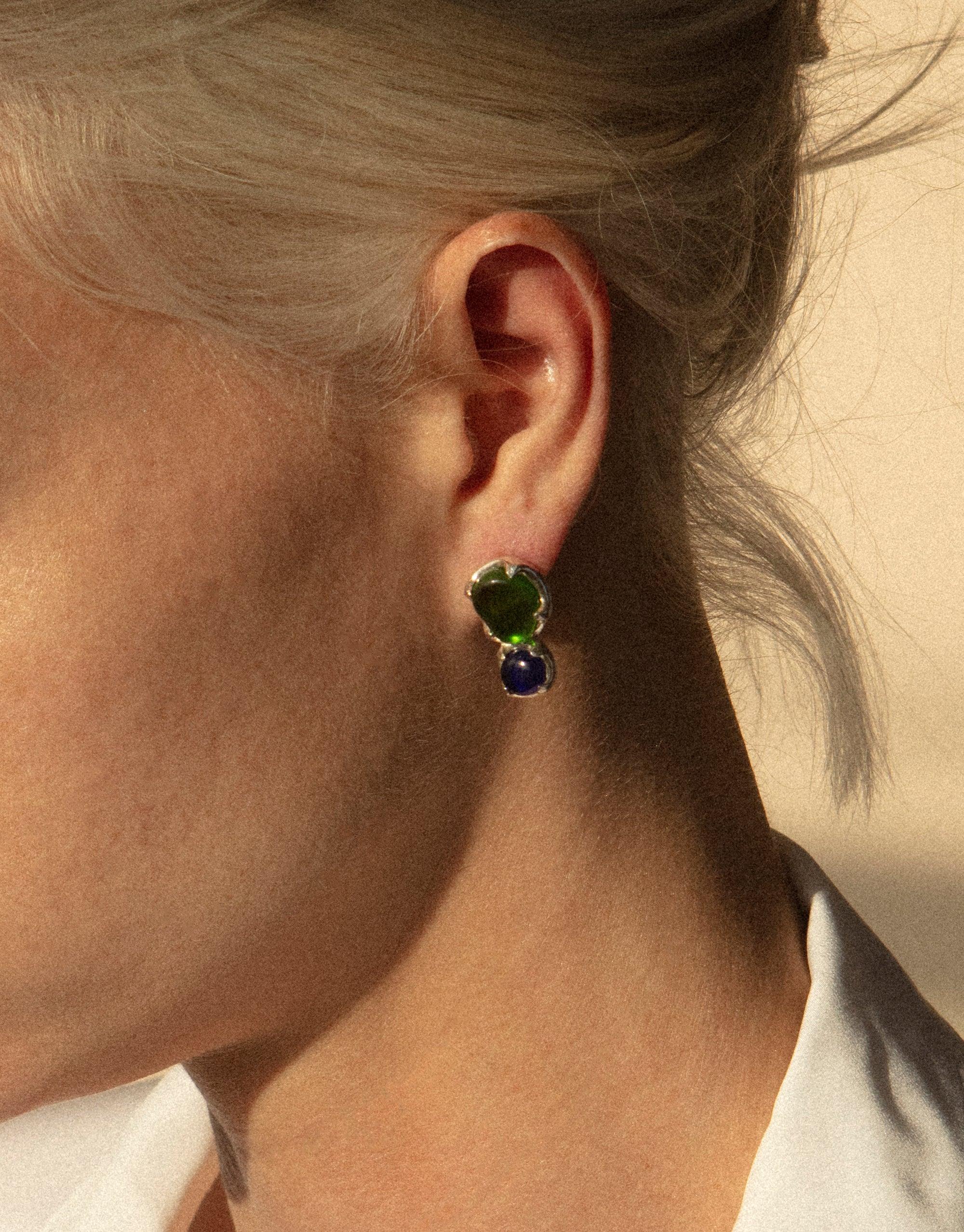 Close-up of an ear wearing Duo Beam Earrings featuring two vibrant eco gems in green and blue, showcasing the prismatic effect of upcycled glass. Elegant and sustainable jewelry design by CLED.