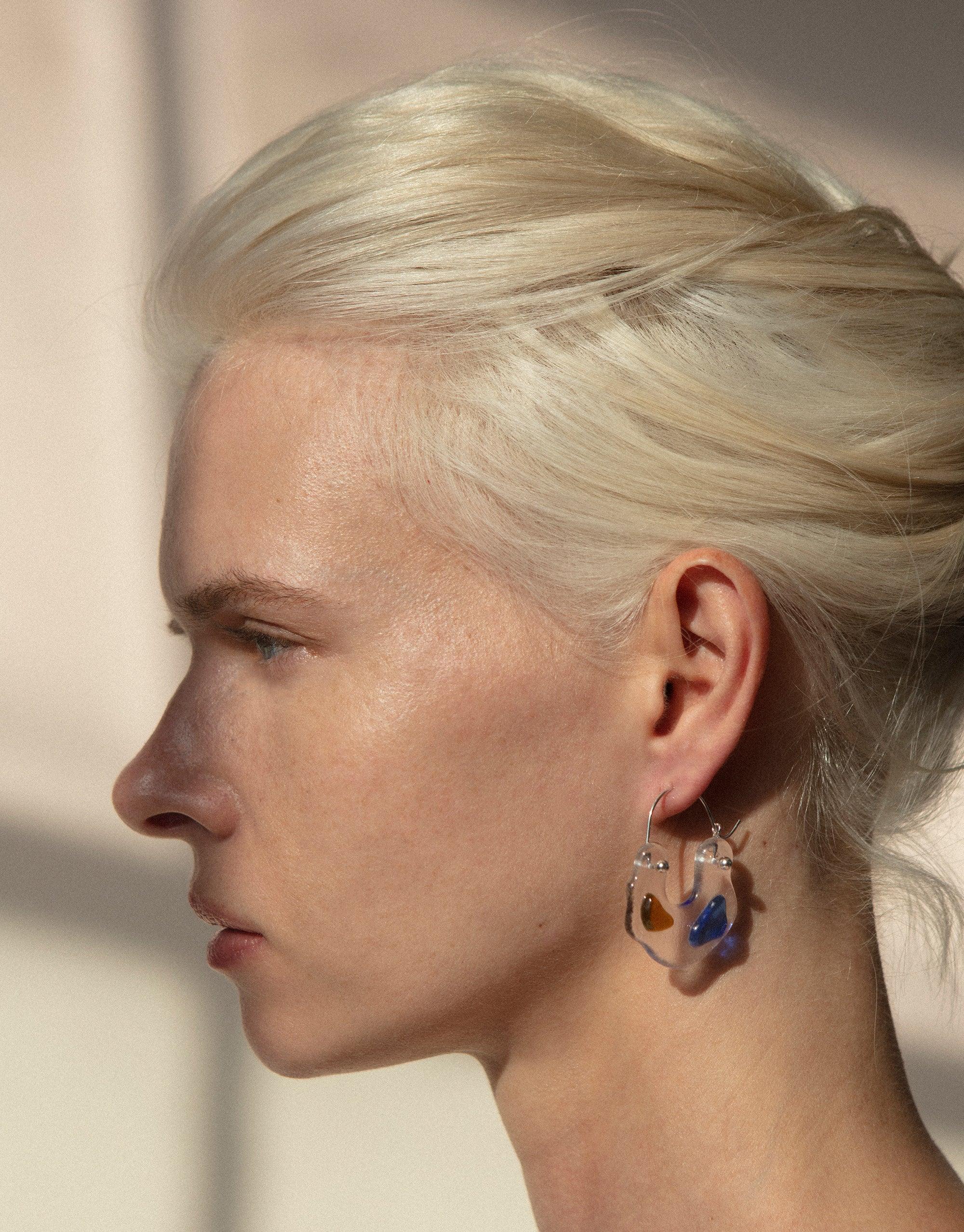 Profile view showcasing Ray Hoop Earrings with colorful eco gems, highlighting the unique spectral colors and handcrafted design. Sterling silver hoops feature upcycled glass elements, embodying sustainable luxury. Ray Hoop Earrings by CLED.