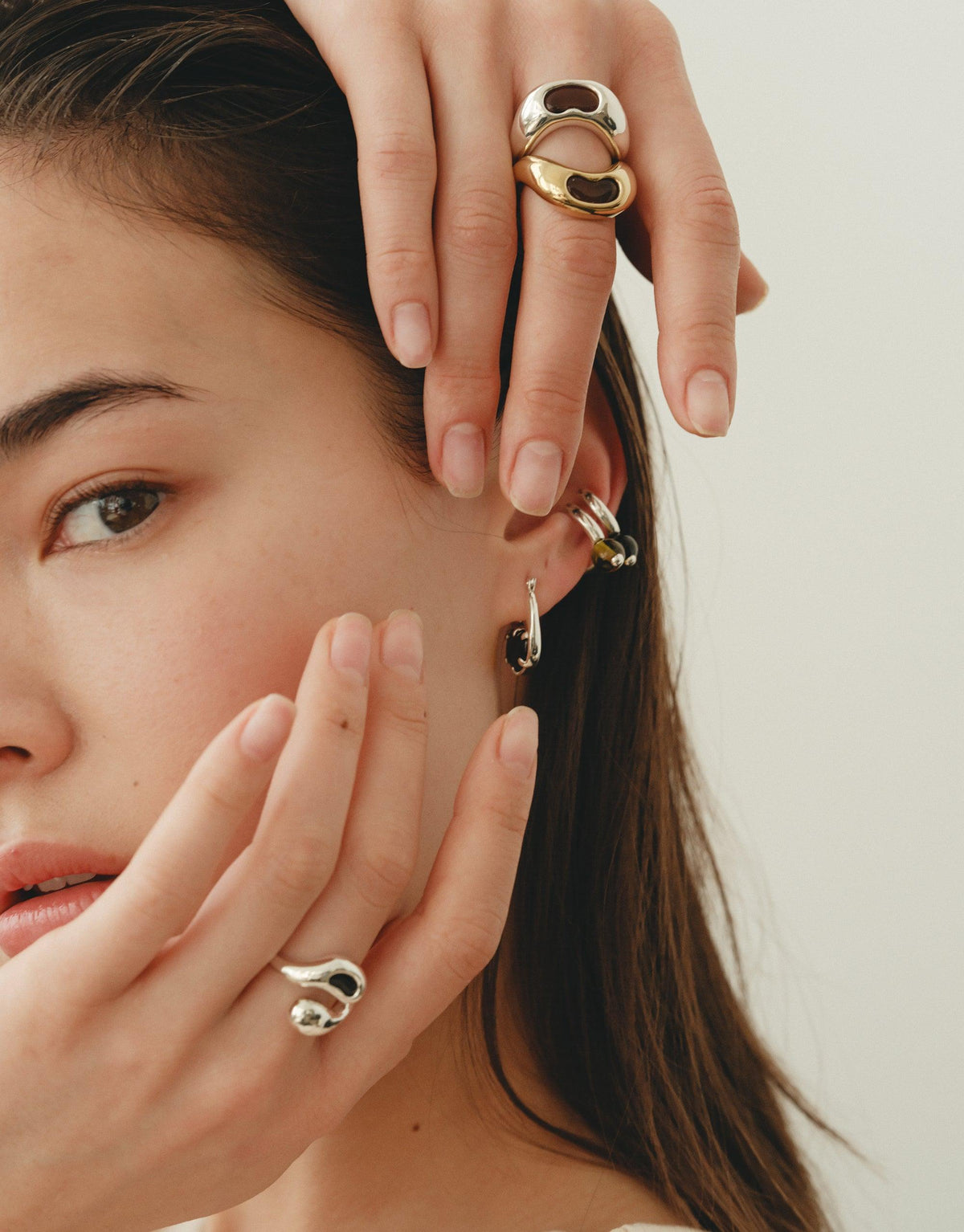 Close-up of a model wearing unique, nature-inspired jewelry including a small pea-shaped ear cuff, rings, and earrings. The jewelry showcases organic shapes and curves, reflecting the beauty of legumes. Pea Ear Cuff | Small by CLED