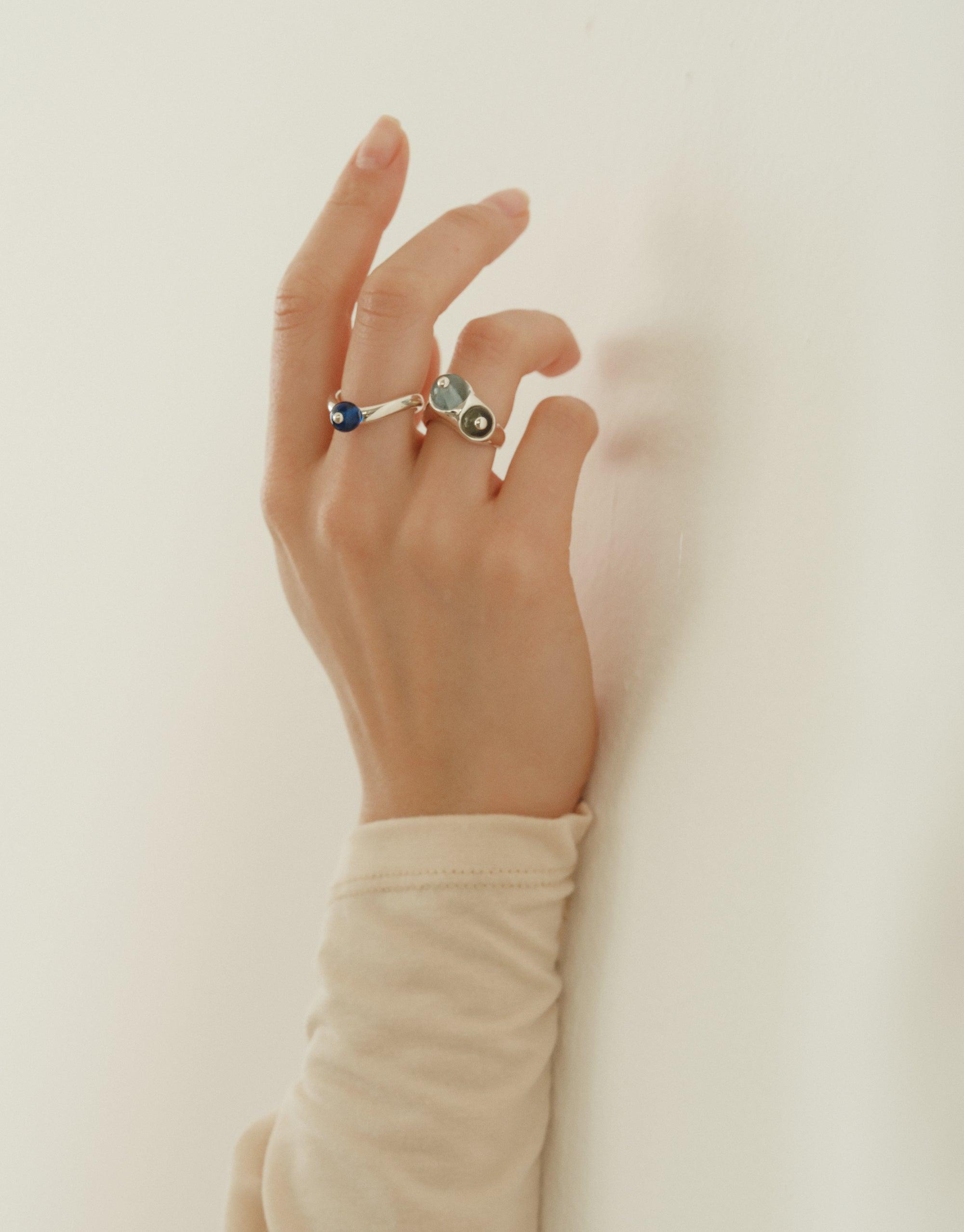 Elegant hand wearing Pod Ring, featuring organic shapes inspired by nature's creativity. Silver band with multiple colorful stones, capturing the essence of legume patterns and soft curves. A unique piece symbolizing growth and transformation. CLED Pod Ring.