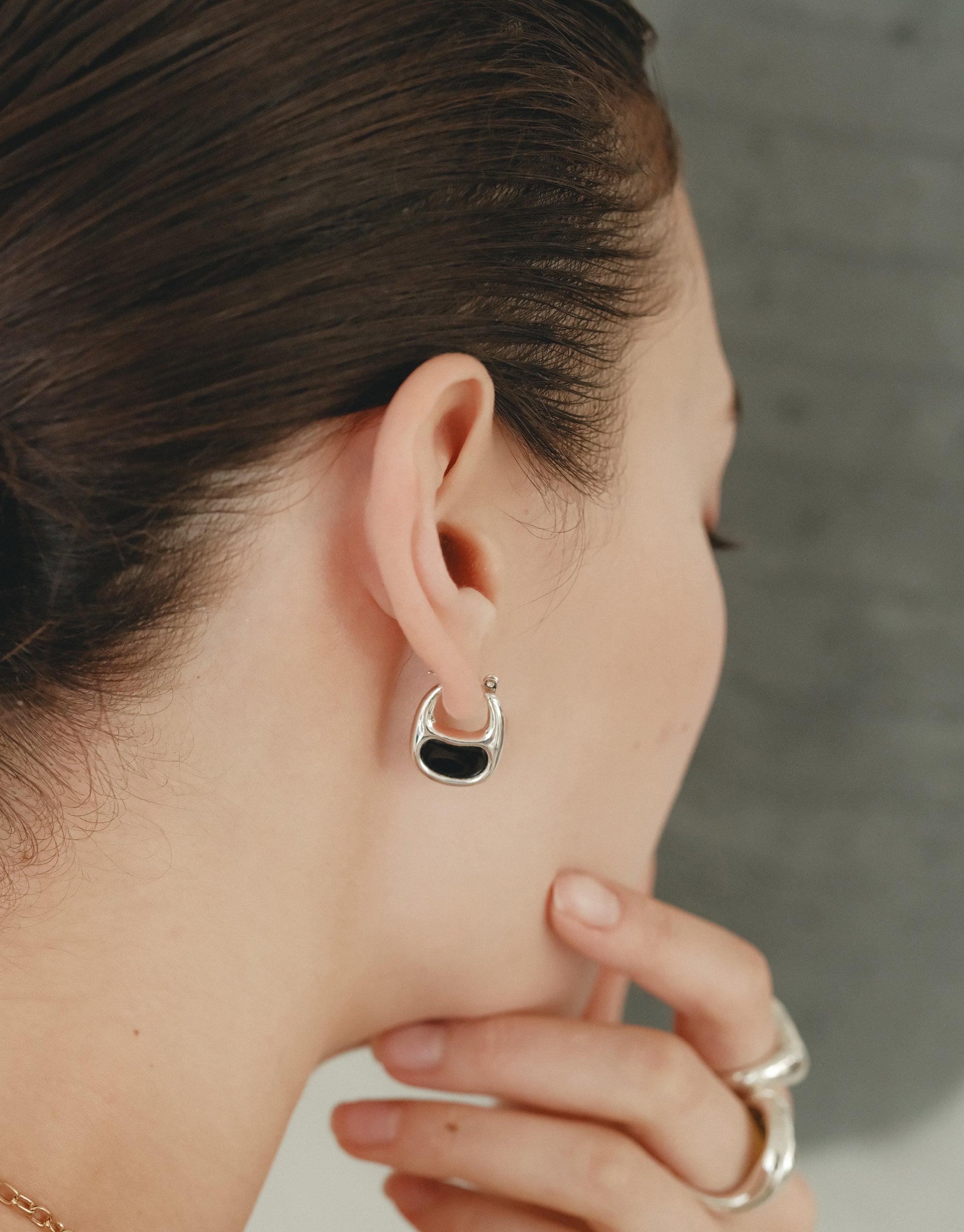Close-up of a woman's ear wearing small, silver-toned Bean Hoop Earrings, showcasing the organic shape inspired by nature's creativity. The earrings complement the model's elegant profile, embodying growth and transformation. Bean Hoop Earrings | Small by CLED