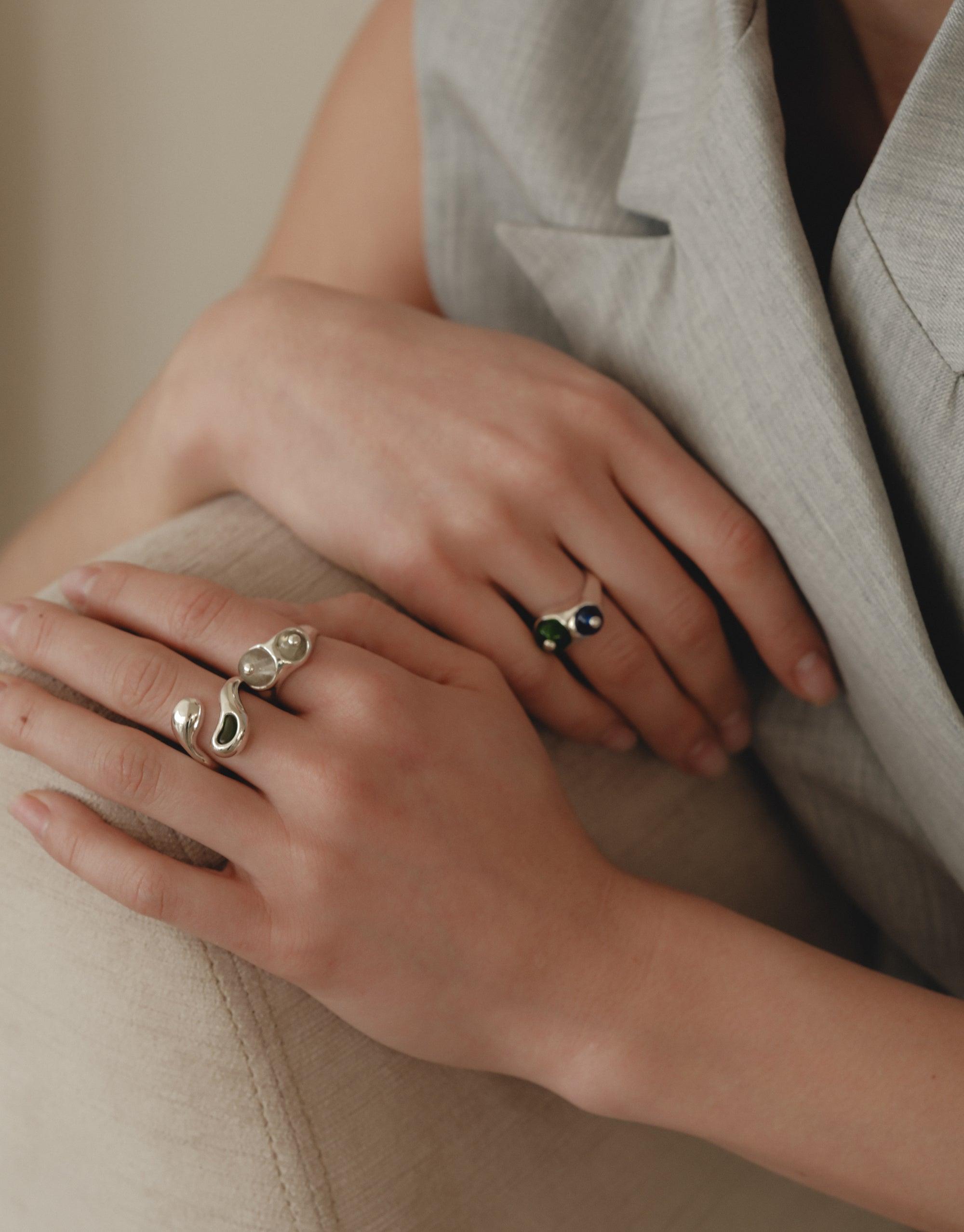 Elegant hands adorned with unique Pod Ring designs, showcasing organic shapes inspired by nature's creativity. The rings feature smooth curves and intricate patterns, reflecting the beauty of legume plants. A perfect blend of natural inspiration and contemporary jewelry design by CLED.