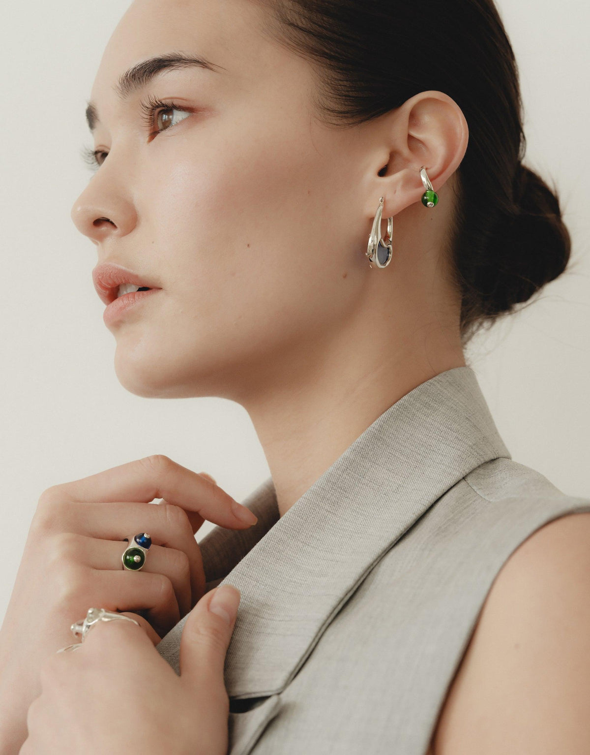Side profile of a person wearing a sleek silver ear cuff and delicate earrings, showcasing the Pea Ear Cuff | Small. The model's elegant pose and neutral-toned attire complement the organic, nature-inspired jewelry design. CLED