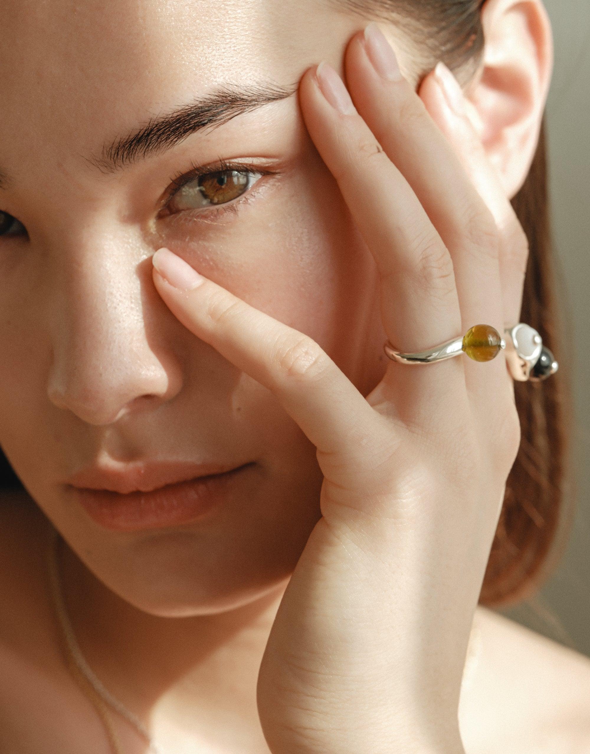 Close-up of a person's hand touching their face, showcasing the Pod Ring with its organic shape and soft curves inspired by nature's creativity. The ring reflects the essence of growth and transformation, embodying the beauty of the natural world. CLED Pod Ring.