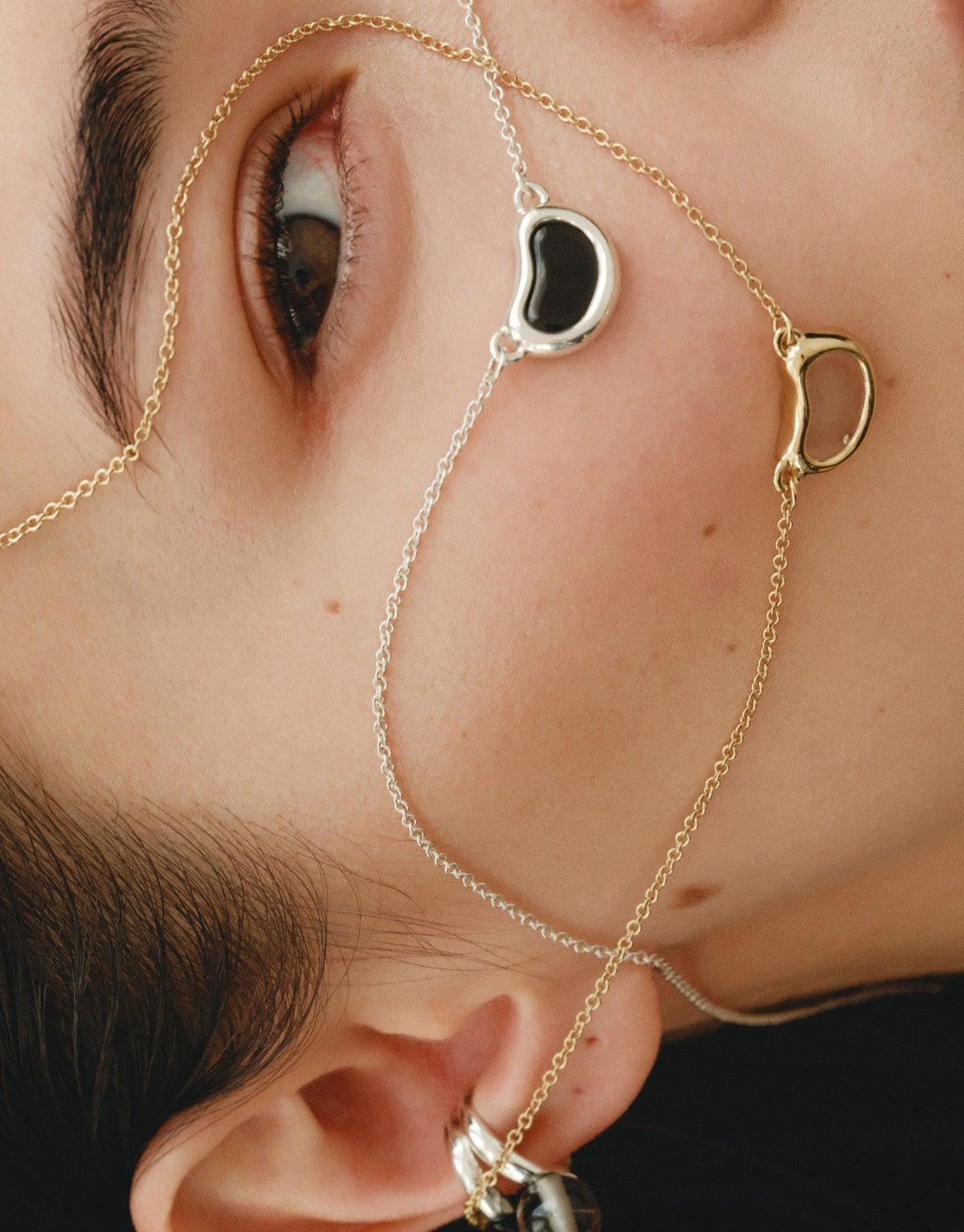 Close-up of Bean Necklace featuring delicate gold and silver chains with organic, bean-shaped pendants. Elegant design inspired by nature's curves and patterns, showcasing the beauty of legume-inspired jewelry. A unique accessory that captures growth and transformation. CLED Bean Necklace.