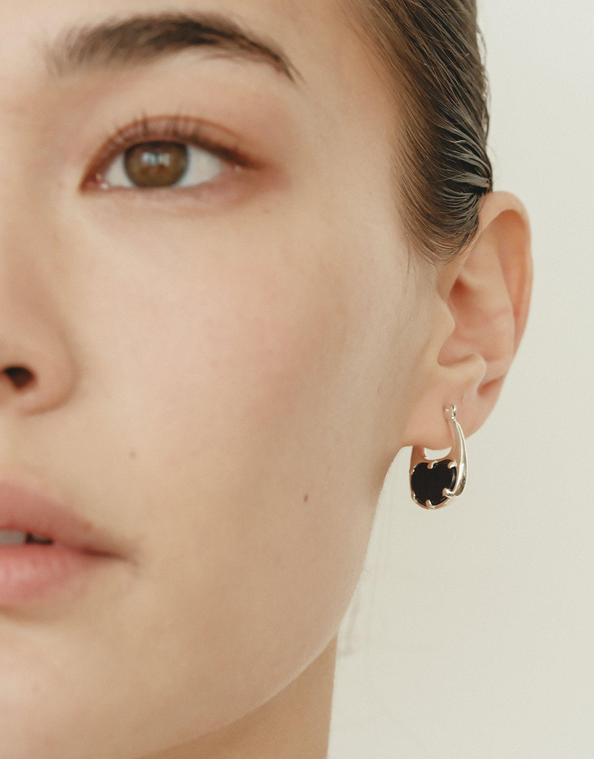Close-up of a model wearing a small, elegant bean-shaped hoop earring in gold, showcasing the organic curves inspired by nature's creativity. The earring's unique design reflects the Bean Hoop Earrings | Small product, capturing the essence of growth and transformation. CLED