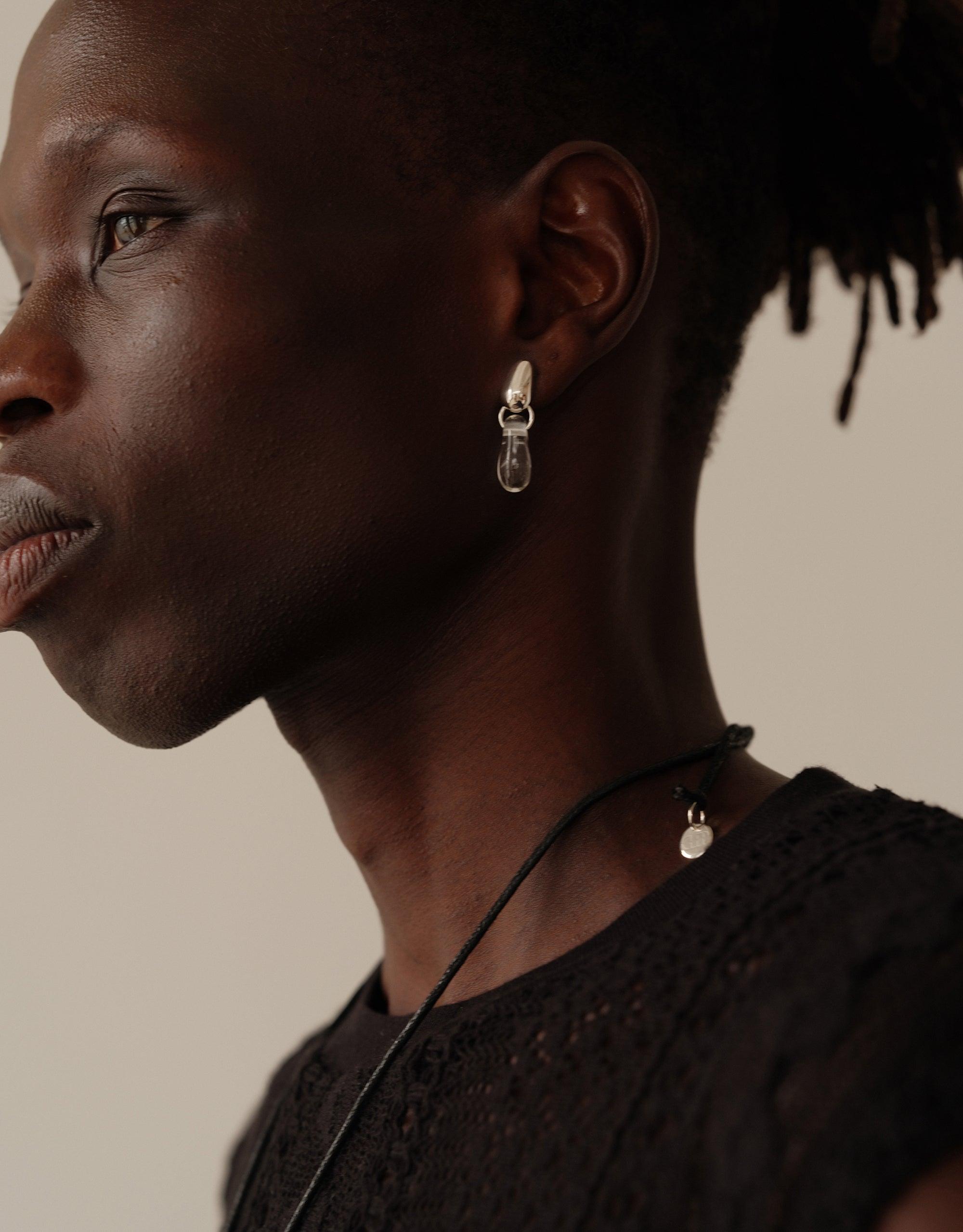 Close-up profile view showcasing Drop Counts Earrings, featuring delicate teardrop-shaped pendants on oval posts. Elegant, minimal design inspired by water, handcrafted from upcycled materials. Sustainable jewelry by CLED.