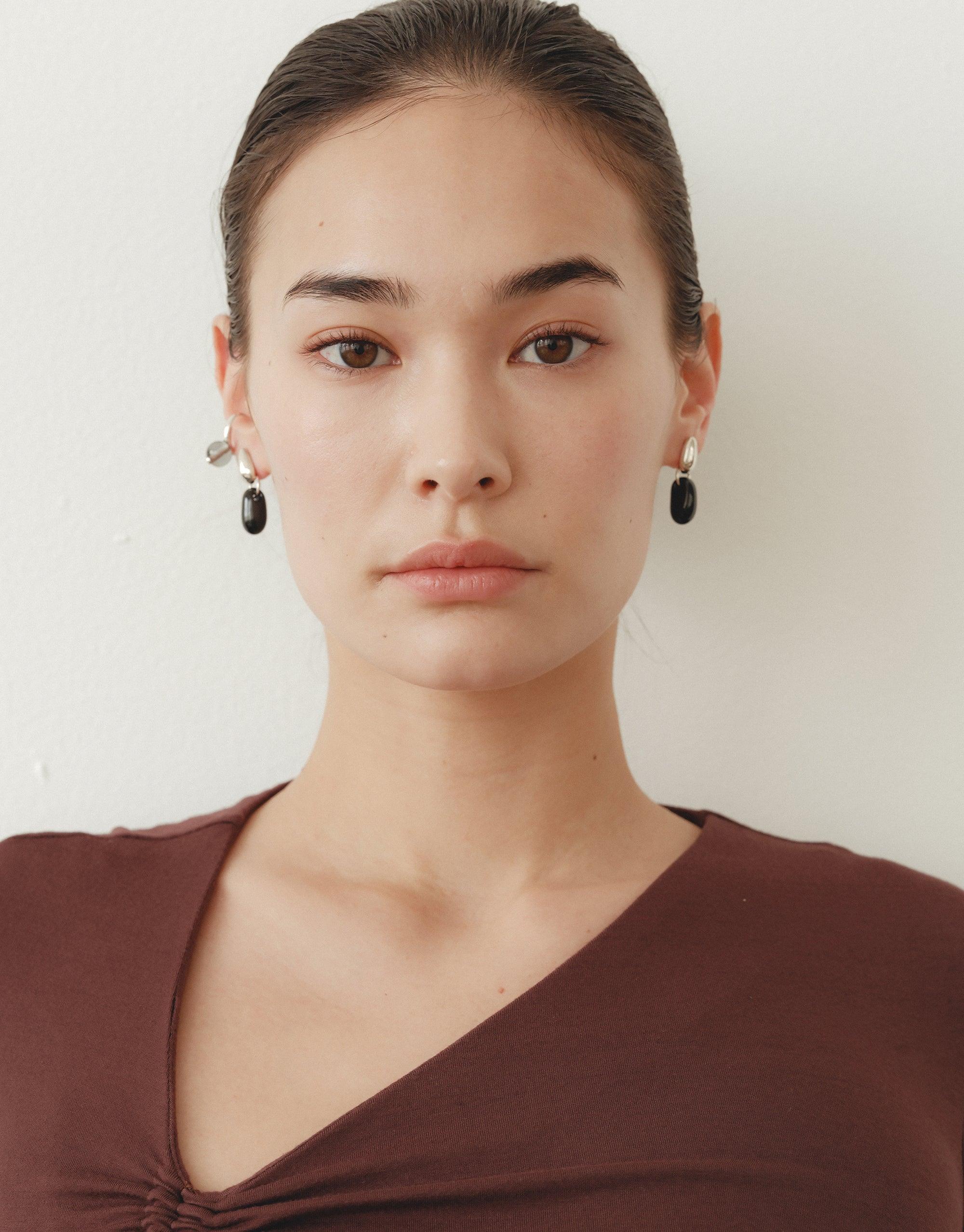 Elegant model wearing Drop Counts Earrings, featuring minimal oval posts with water-inspired drop design. Handcrafted from upcycled glass, these earrings showcase sustainable luxury in sterling silver or gold vermeil. Eco-friendly jewelry by CLED.