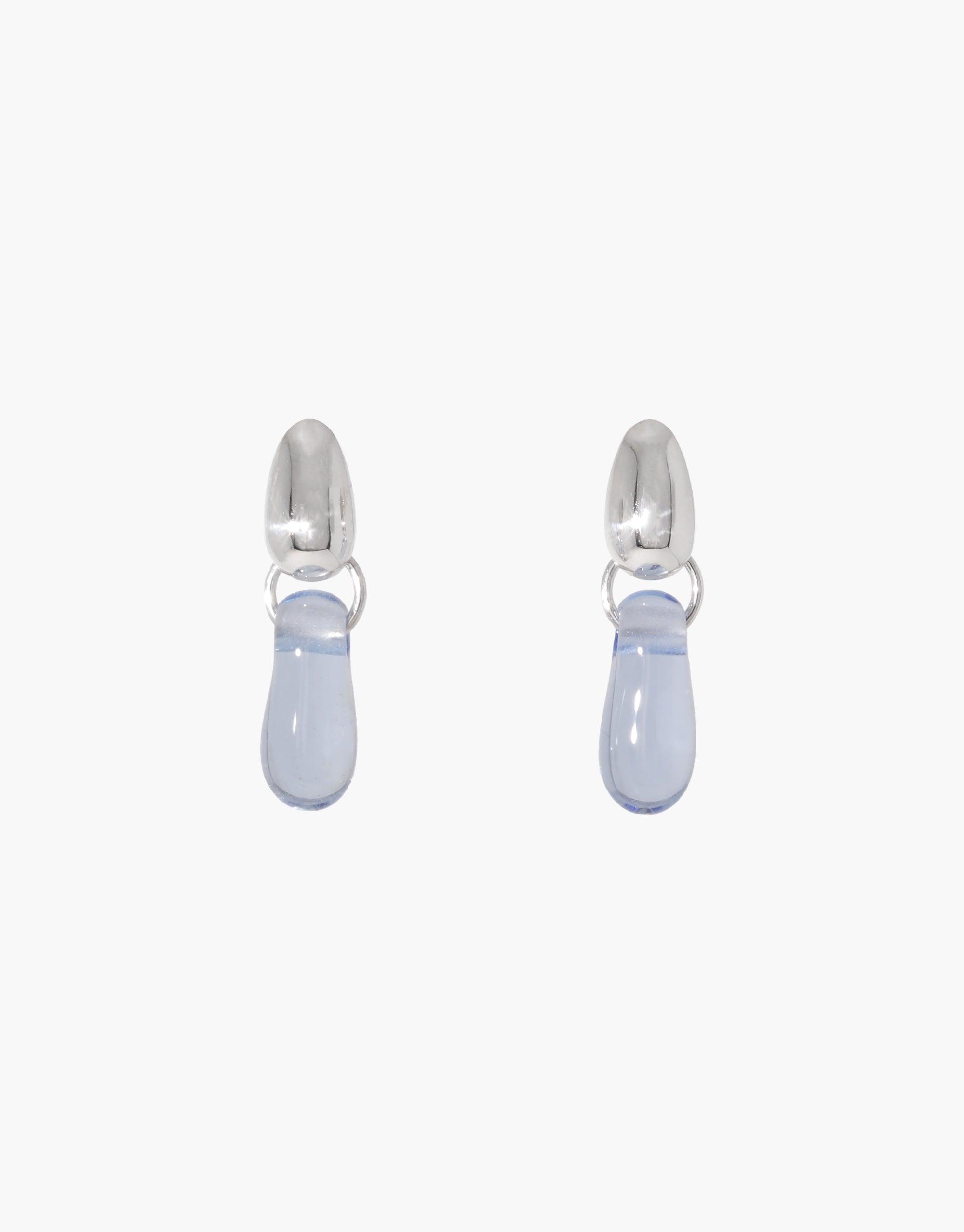Elegant Drop Counts Earrings featuring pale blue teardrop-shaped pendants suspended from silver oval posts, showcasing a minimalist design inspired by water droplets. Handcrafted from upcycled eco-friendly materials, these earrings embody sustainable luxury. CLED Drop Counts Earrings.