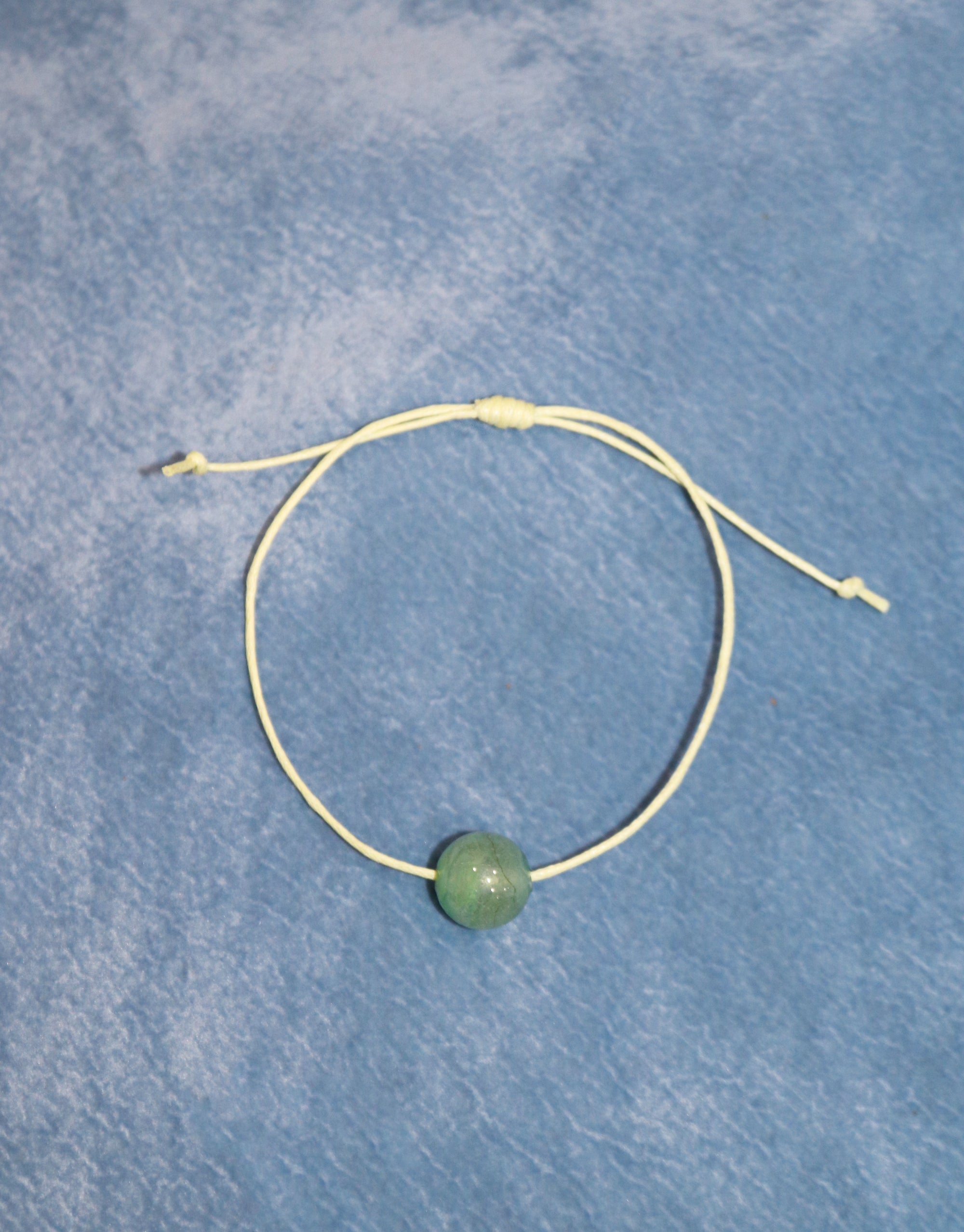 A bracelet featuring a beautiful green stone with light yellow thread