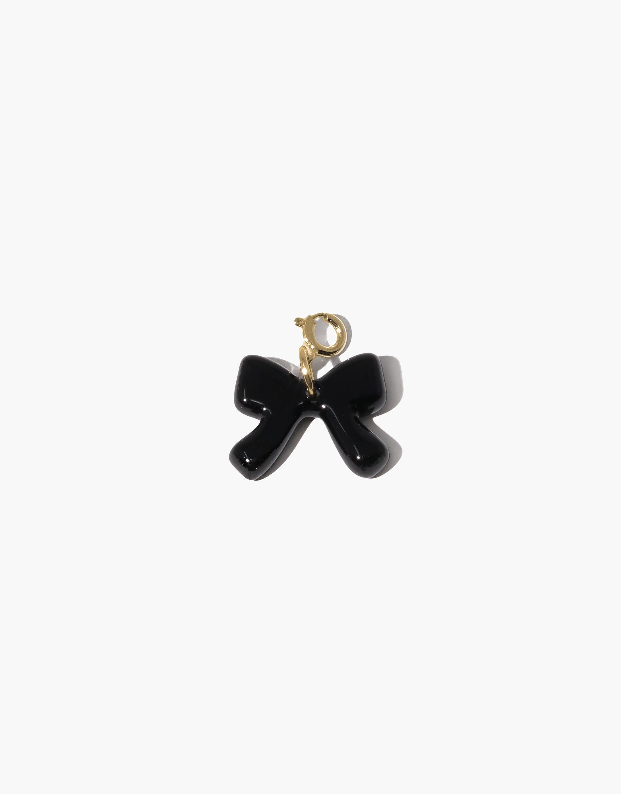 Elegant black bow charm with gold-toned clasp, perfect for adding a playful touch to necklaces or bracelets. Icon Charm collection piece featuring a glossy finish and distinctive shape. Bow A | Icon Charm by CLED
