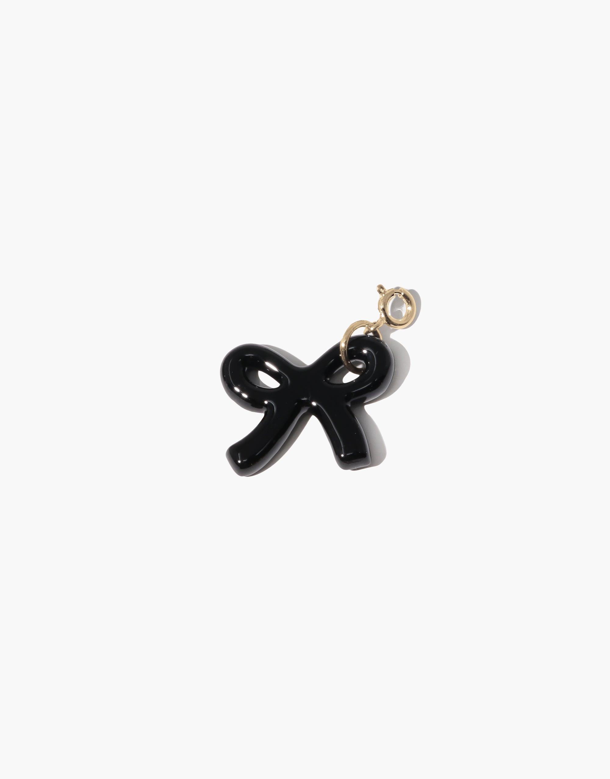 Elegant black bow-shaped charm with gold clasp, perfect for adding playful style to necklaces or bracelets. Bow B Icon Charm from CLED's collection of distinctive and fun jewelry accessories. CLED