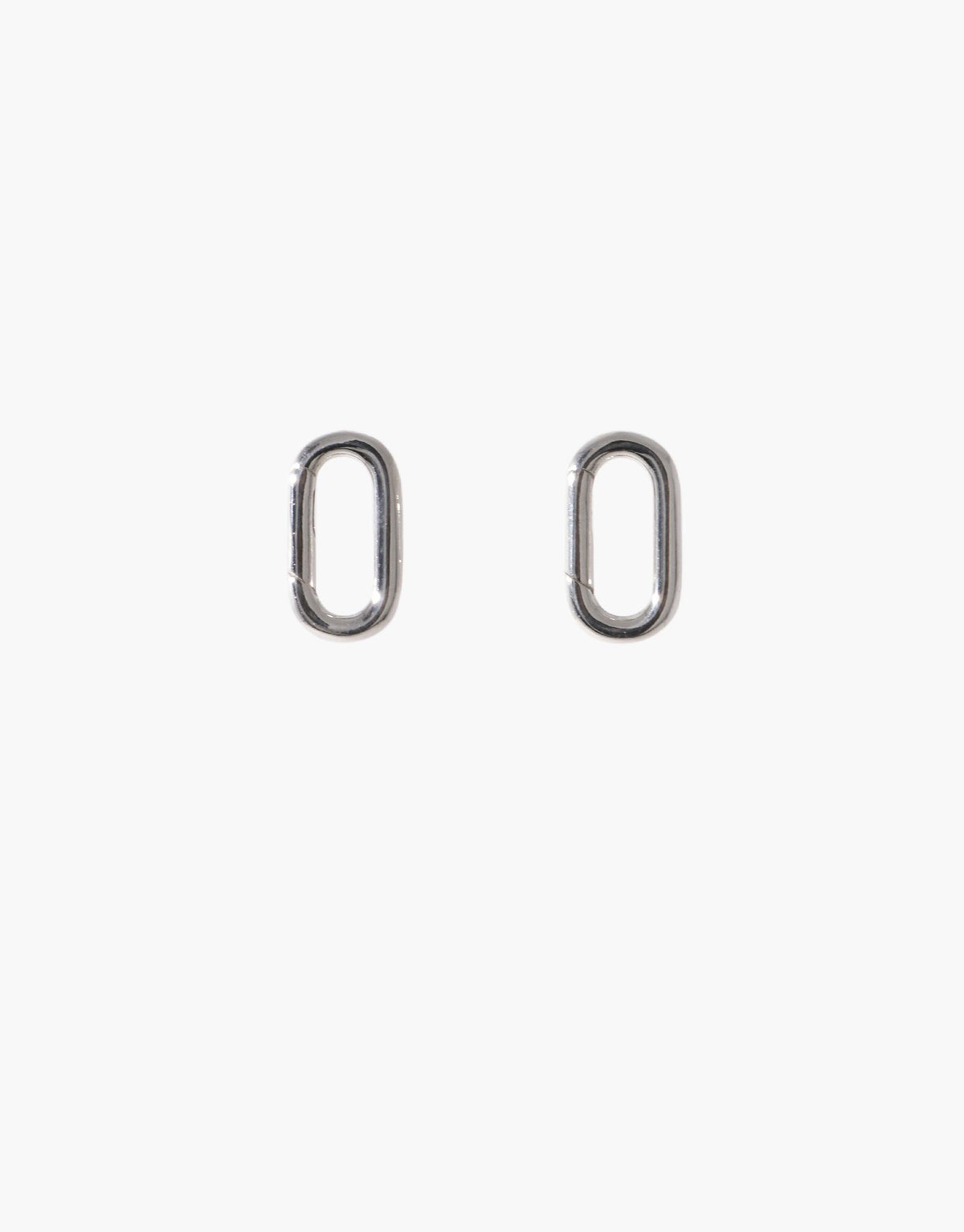 Loop Stud Earrings in silver-toned metal, featuring an oval-shaped design with an open center. These versatile earrings allow for attaching interchangeable charms, offering customizable styling options. Perfect for creating unique looks with various Icon Charms. Loop Stud Earring by CLED.