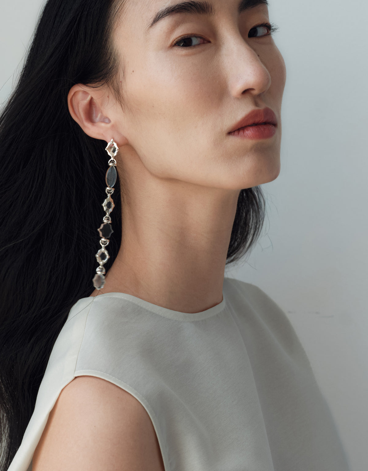 Cadence Linear Earring in black basalt glass worn in profile, dark Eco Gems linked along a sterling silver line. Handmade in Los Angeles. Cadence Linear Earring by CLED.