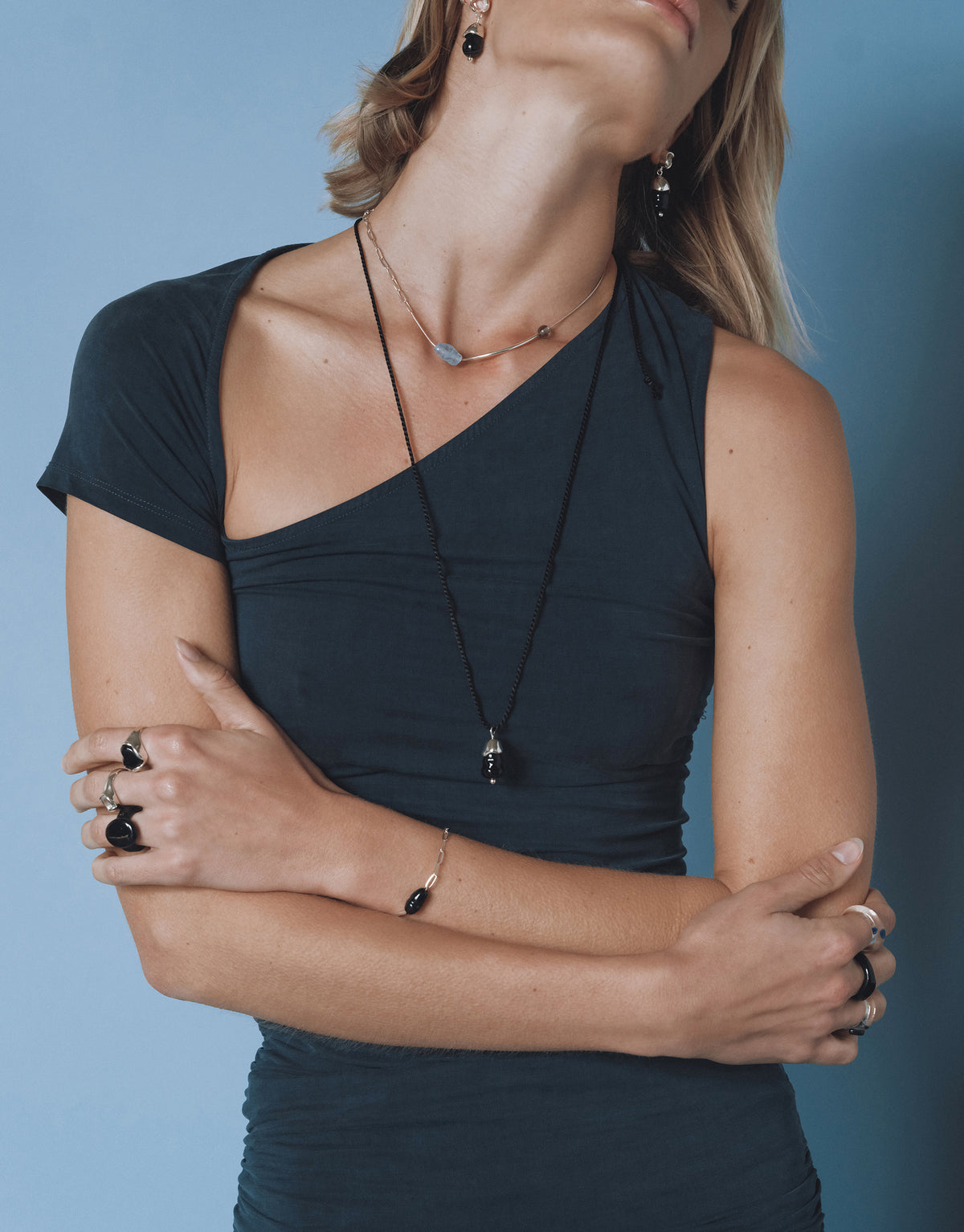 Still Necklace layered with silver chains and glass beads, styled with black top against blue background - CLED