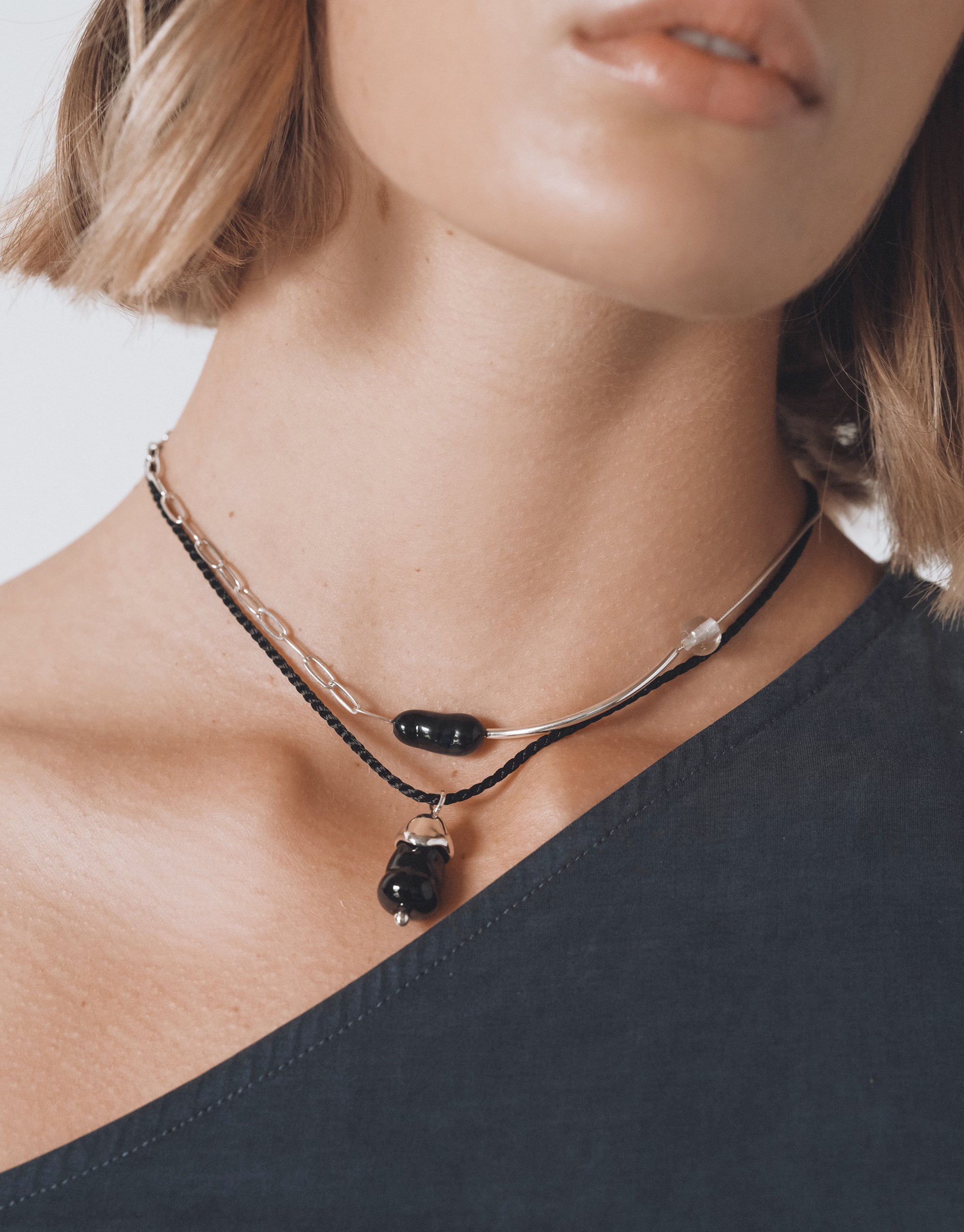Still Necklace layered silver choker with black glass beads and asymmetrical curved design worn on neck by CLED