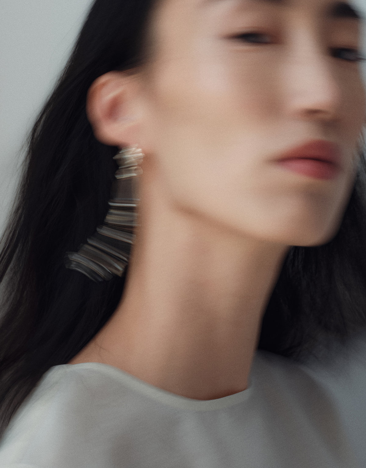 Cadence Linear Earring in motion, the long drop of upcycled glass Eco Gems blurring as the head turns. Cadence Linear Earring by CLED.