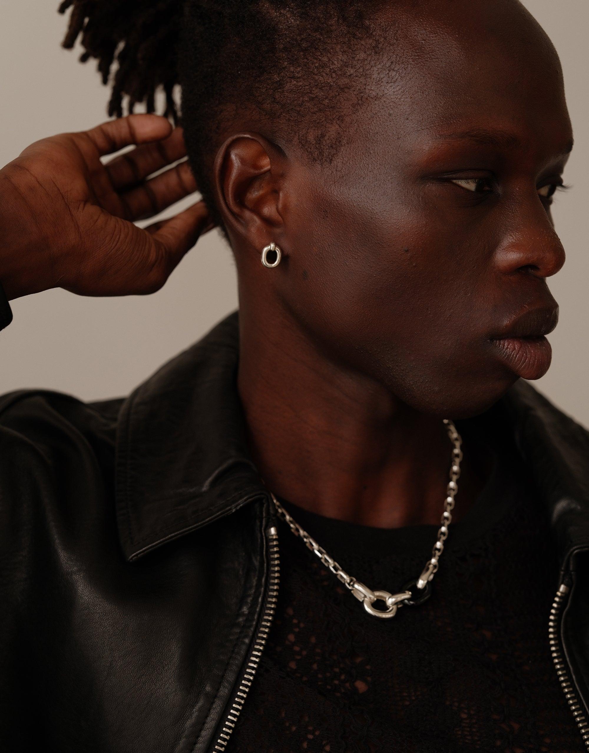 Profile view of person wearing small silver hoop earrings and chain necklace, styled with black leather jacket, showcasing Core Loop Earrings | Small from sustainable jewelry collection by CLED