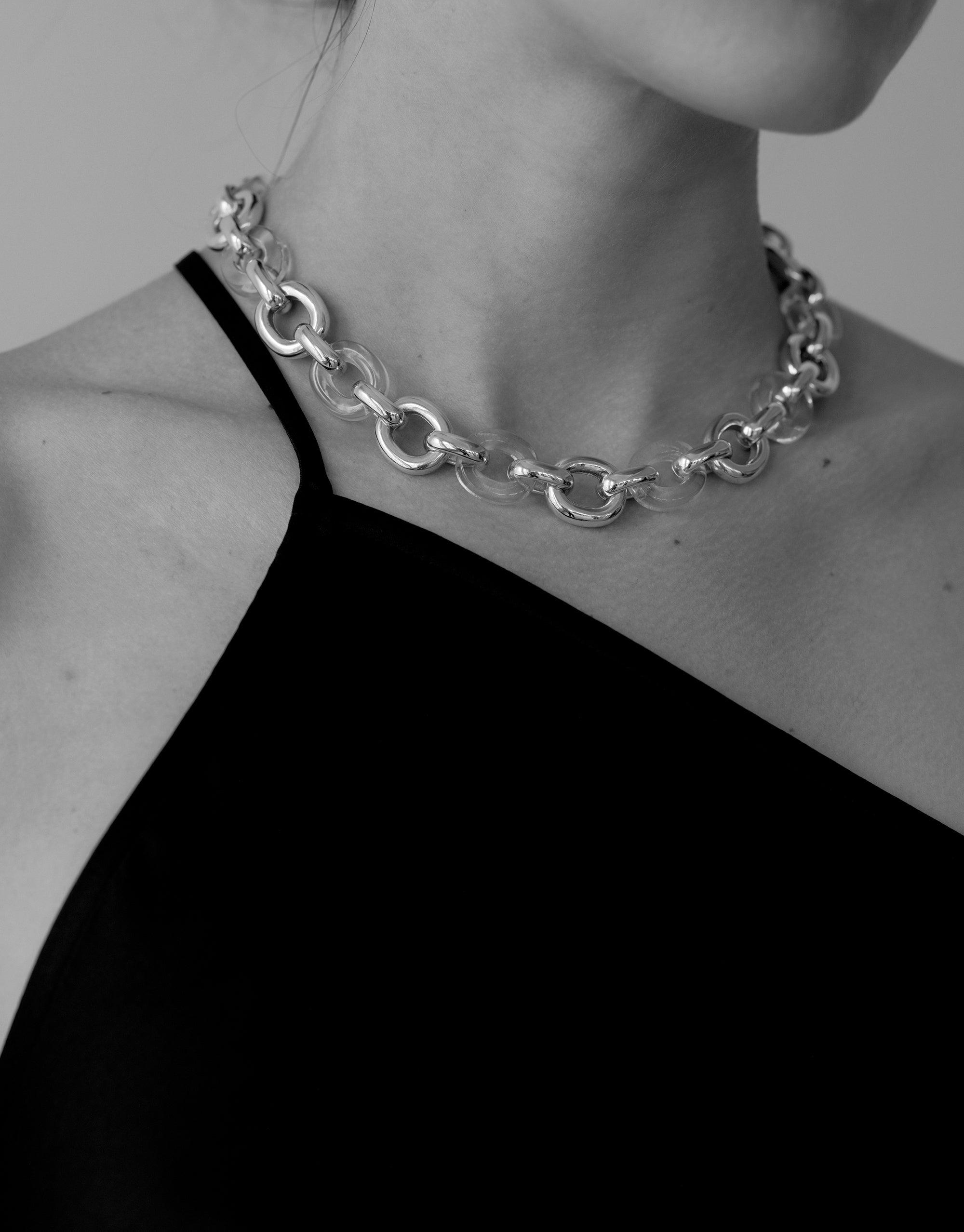Connected Loop Necklace in mixed metal and glass, showcasing interlocking circular links. Elegant and bold statement piece worn against a black top, symbolizing unity and upcycling. Sustainable fashion accessory from the In The Loop collection by CLED. Connected Loop Necklace | Mixed Metal & Glass.