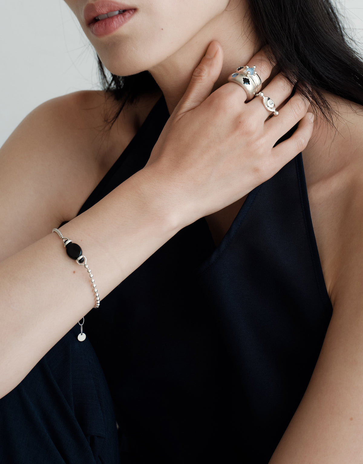 LAS Oval Swivel Ring | Metal worn on the model, a hand raised to the neck with stacked sterling silver rings. Handmade in Los Angeles. LAS Oval Swivel Ring | Metal by CLED.
