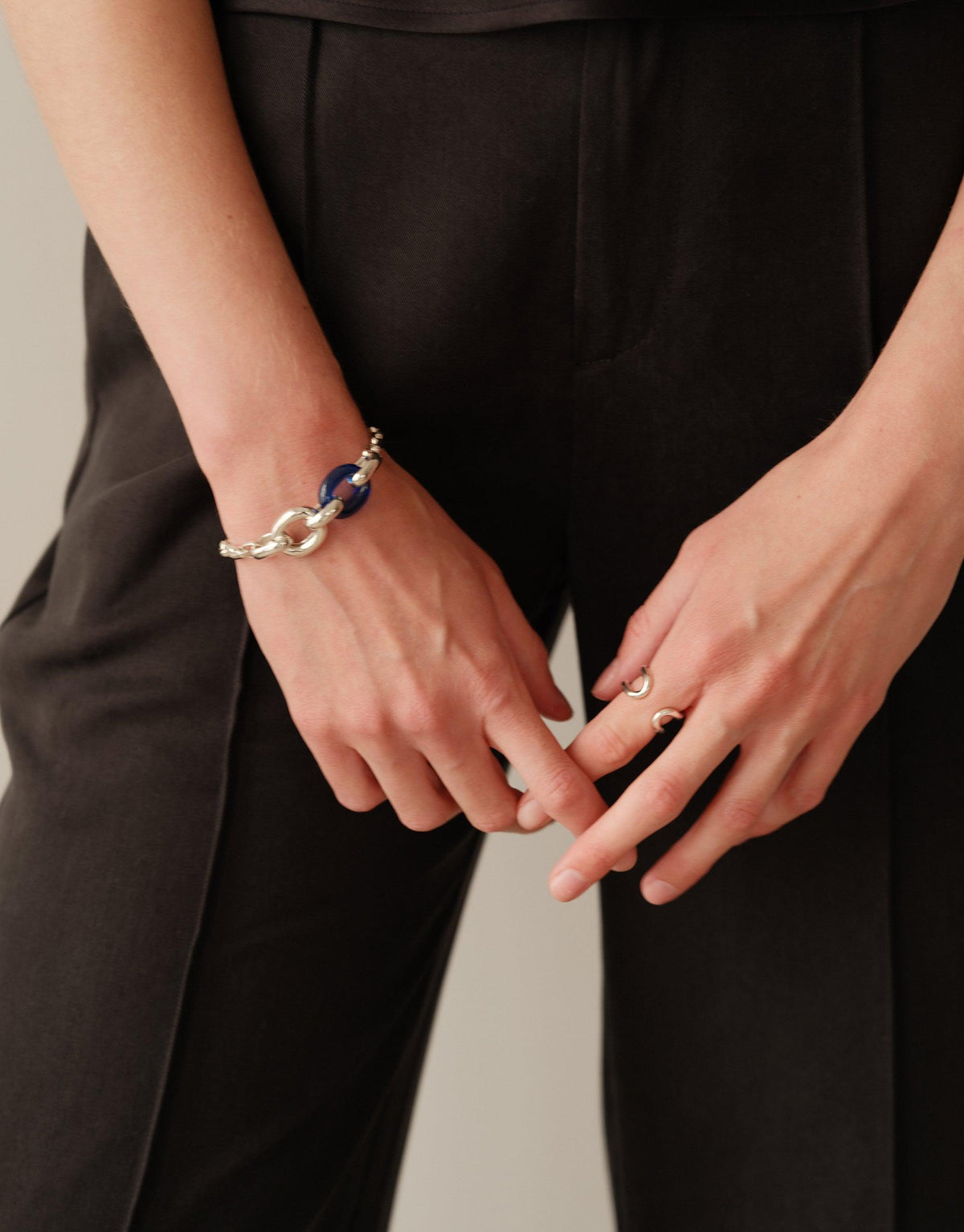 Elegant Loop Hook Bracelet on model's wrist, featuring a unique blue and silver design. Paired with black trousers, showcasing the bracelet's versatility and style. Part of the In The Loop collection, symbolizing unity and upcycling. Loop Hook Bracelet by CLED.
