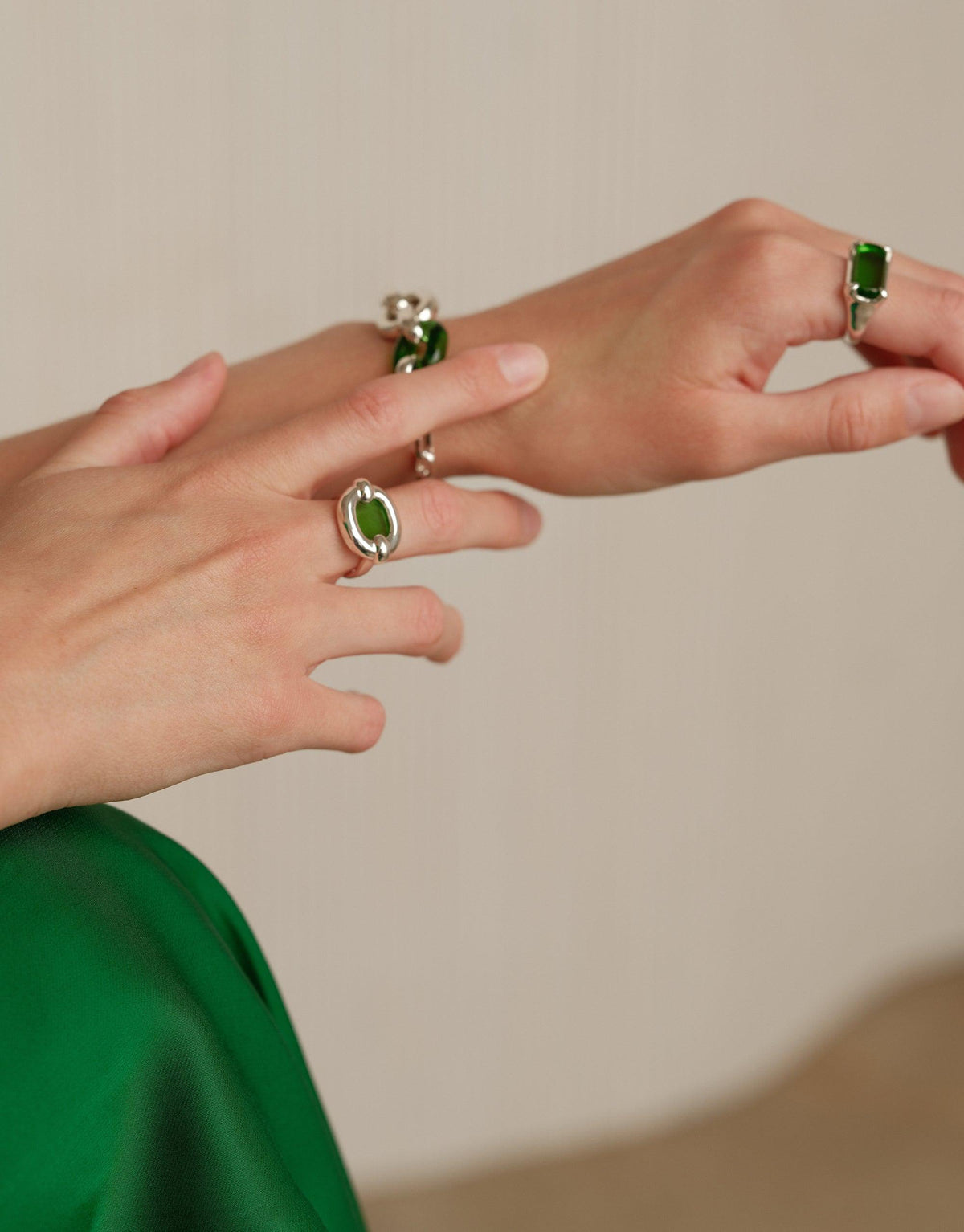 Elegant hands wearing three Core Loop Rings with green eco gems set in silver metal. The rings showcase a unique seamless setting technique, highlighting the mirror-like finish and functional design. Perfect for capturing reflections or quick touch-ups. Core Loop Ring | Large by CLED