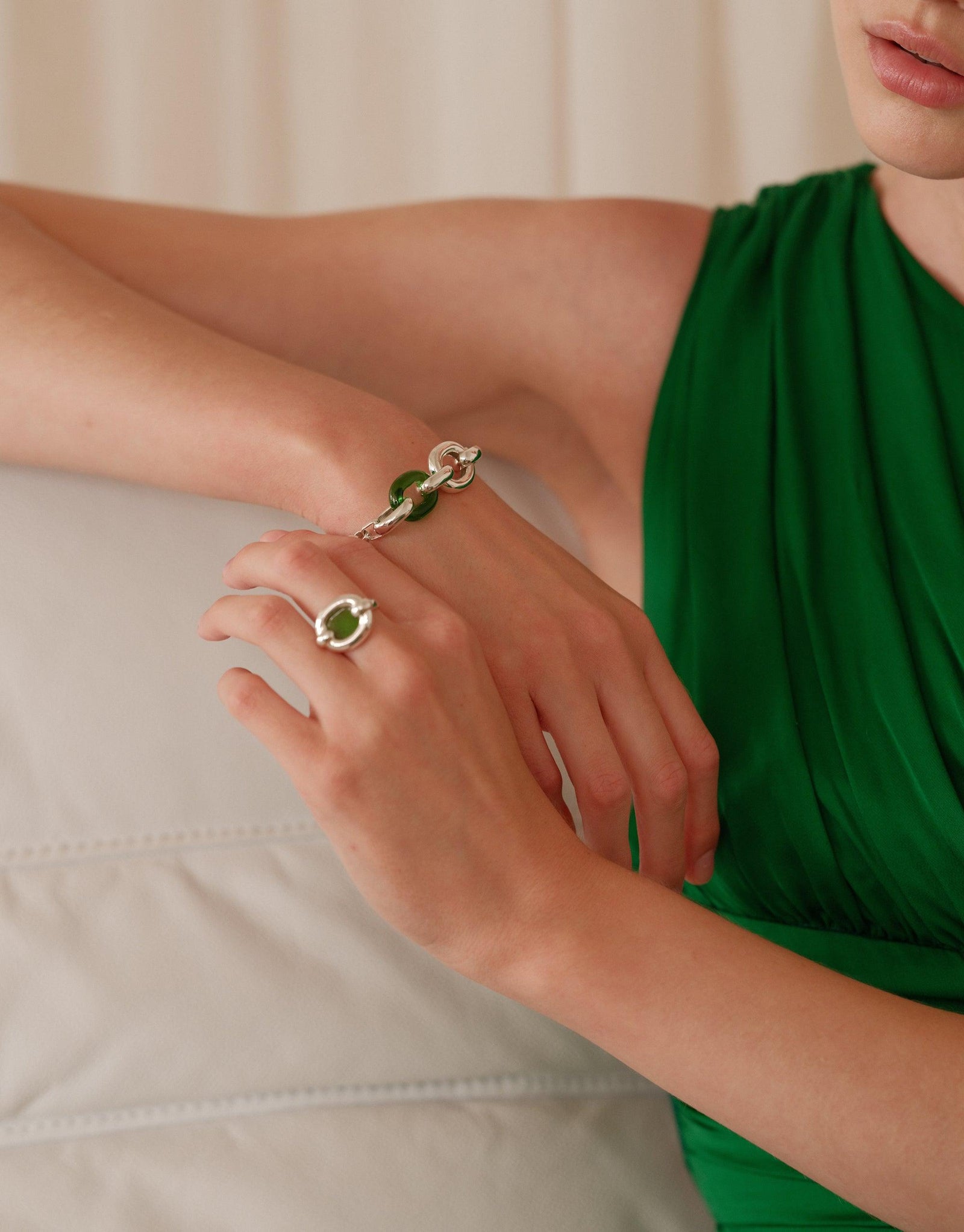 Close-up of hands wearing elegant Core Loop Ring | Large, showcasing its seamless metal setting with eco gem center. Stylish accessory paired with green dress, highlighting the ring's versatile design and mirror-like functionality. CLED