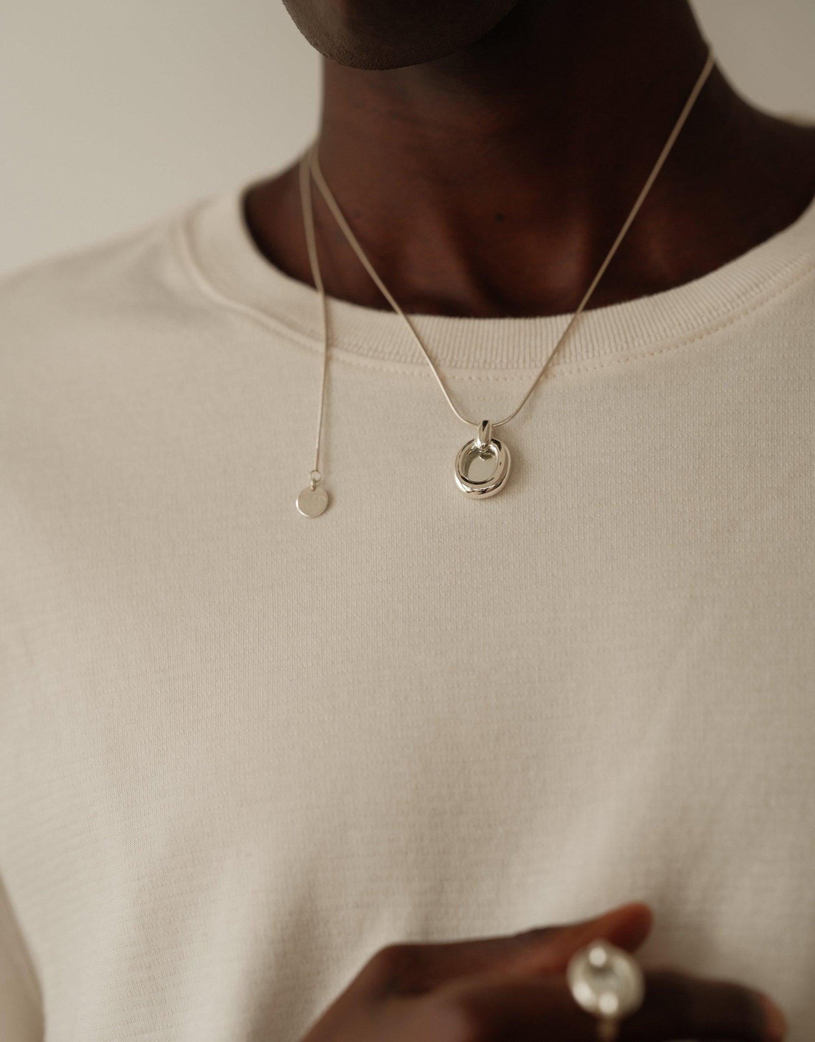 Elegant Core Loop Necklace with snake chain displayed on model wearing white shirt. Minimalist design featuring circular pendant, symbolizing unity and connection. Sustainable jewelry piece from the Loop Collection. Core Loop Necklace | Snake Chain by CLED