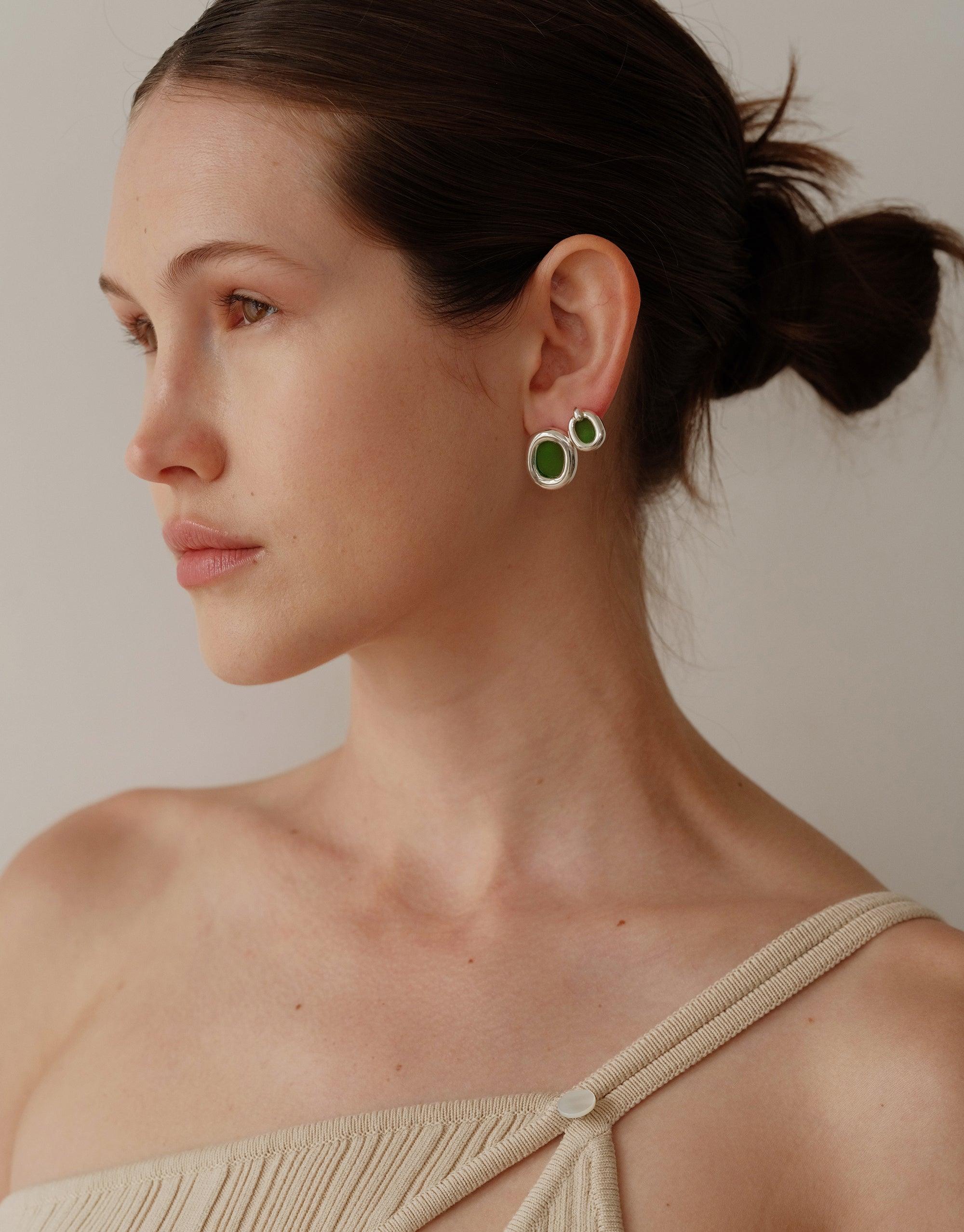 Profile view of model wearing small circular earrings with green accents, showcasing the Core Loop Earrings | Small. Elegant and minimalist design reflects upcycling ethos and unity theme of the Loop Collection. CLED