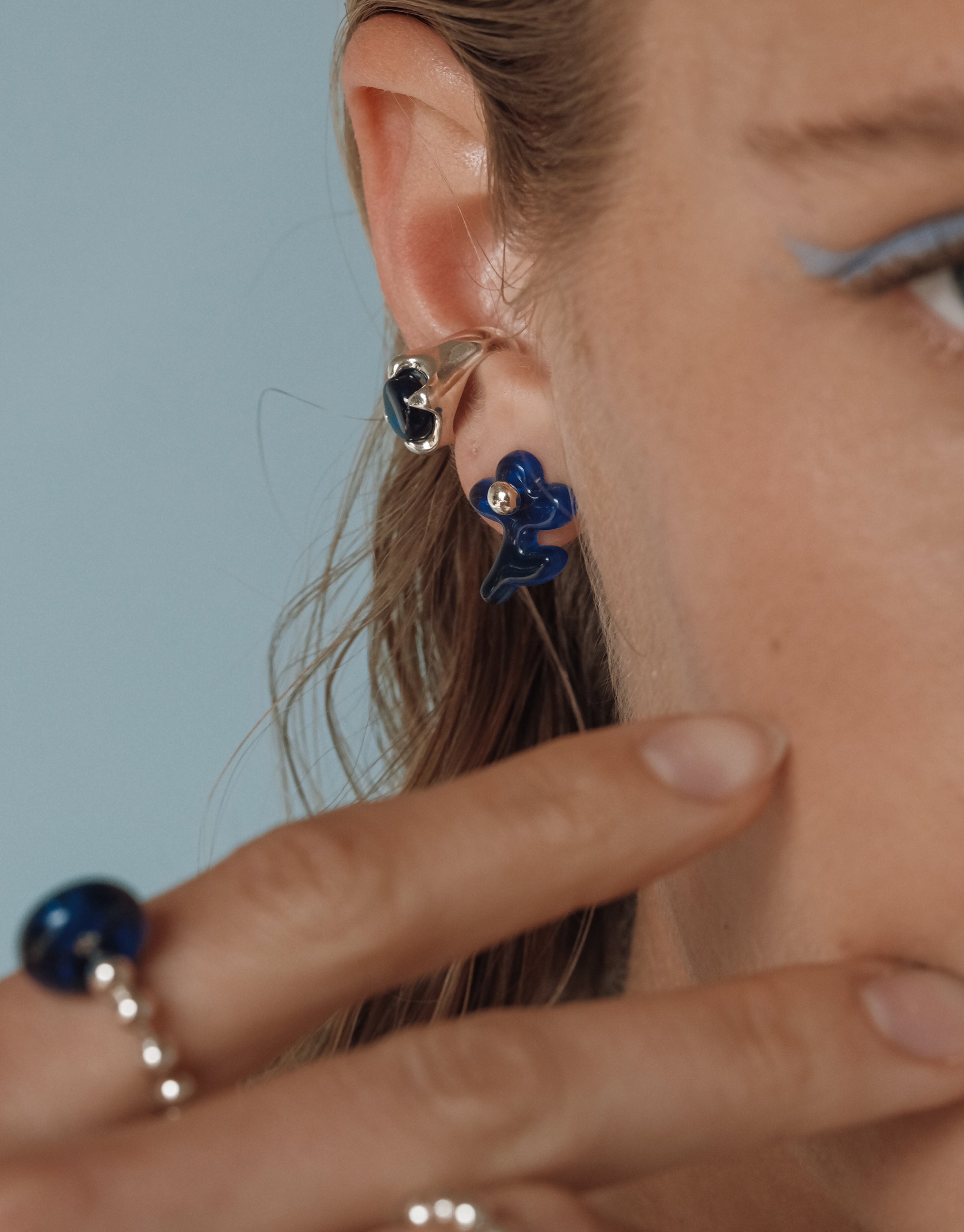 Asymmetrical navy blue floral Petal Icon Stud Earrings with silver accents shown on ear, from Goyo Serenity Collection by CLED