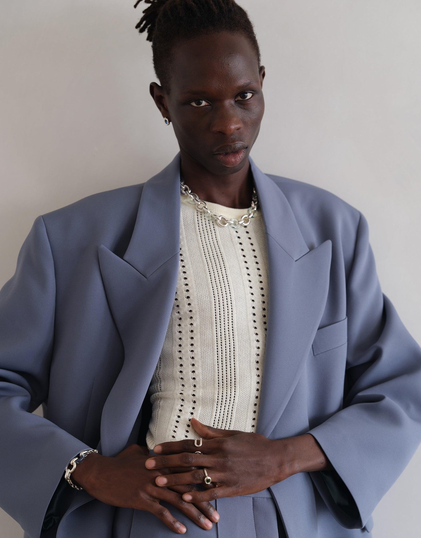 Elegant model wearing oversized blue blazer and cream sweater, displaying multiple rings including the Core Loop Ring | Small. Stylish jewelry showcasing upcycled design concept by CLED.