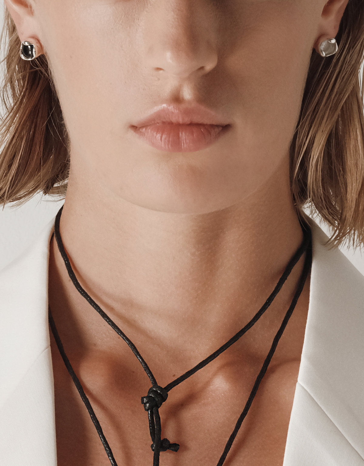 Eco-friendly Orb Stud Earrings with silver bezel settings and clear cabochon stones shown on model wearing white blazer - CLED