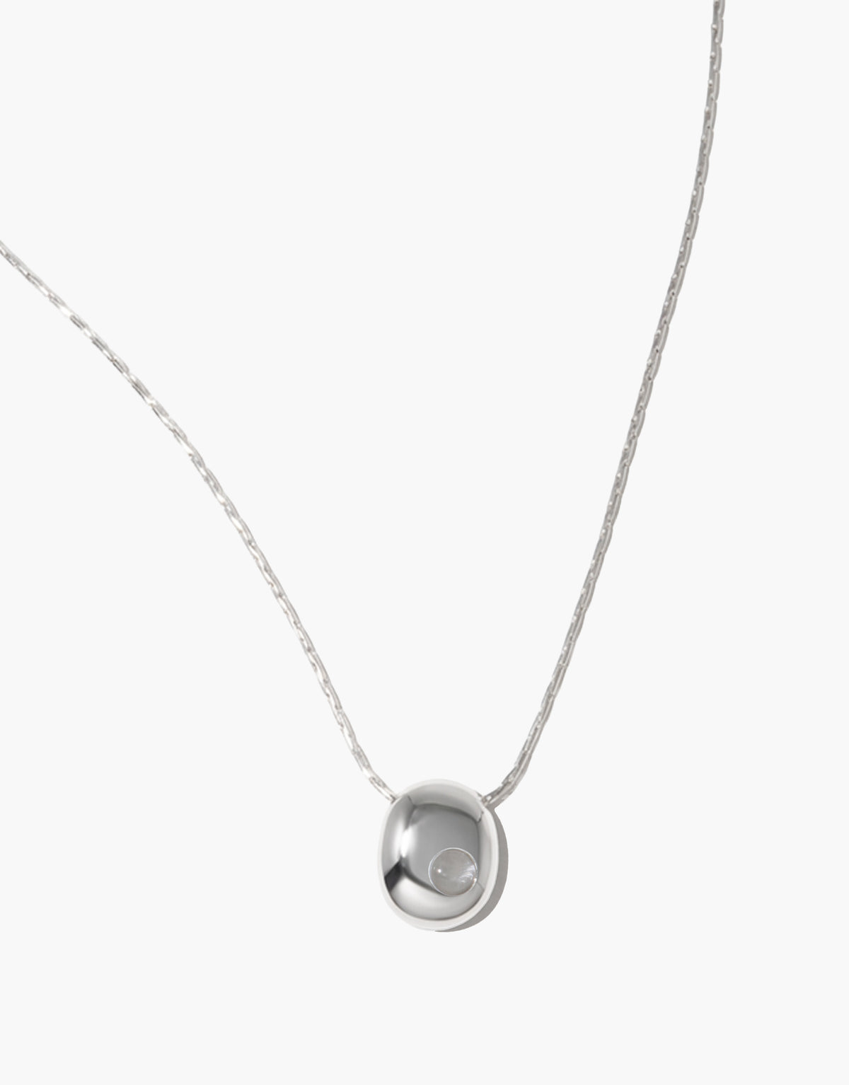 Close view of the Inter Loop Necklace pendant, a smooth sterling silver dome cradling a clear air glass Eco Gem, strung on a delicate chain. Inter Loop Necklace by CLED.