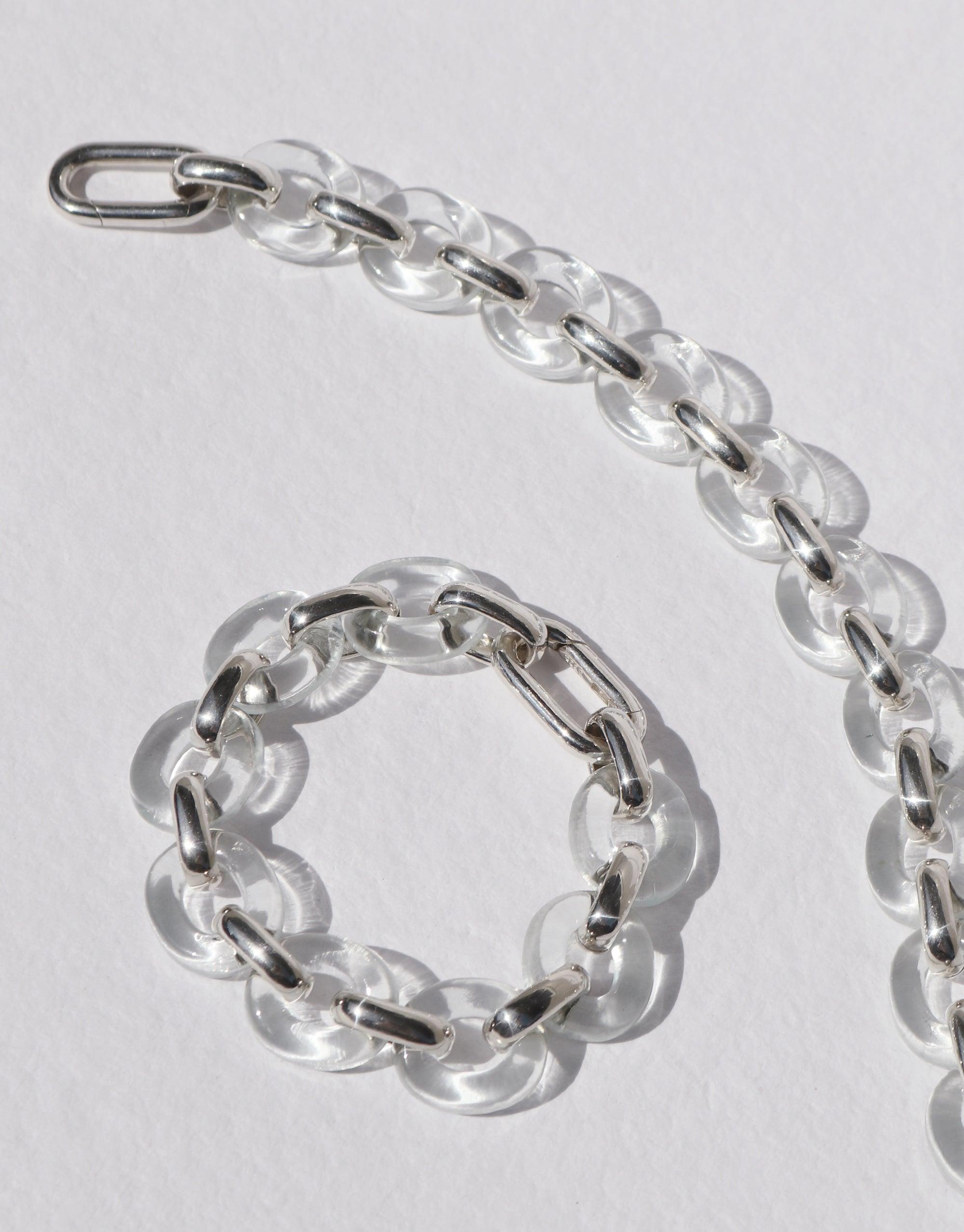 Connected Loop Bracelet featuring clear glass links interconnected with silver-toned metal, symbolizing unity and upcycling. The bracelet forms a circular shape, reflecting the continuous loop design. Elegant and sustainable jewelry piece by CLED.