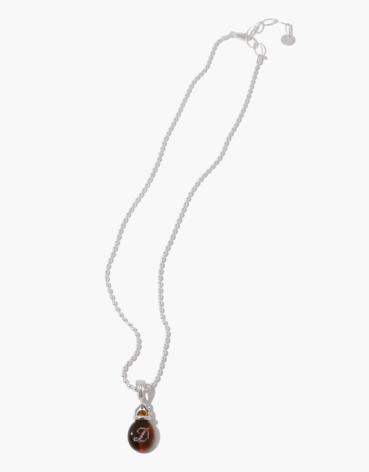 A silver beaded necklace with a teardrop-shaped brown pendant featuring a white monogram logo, displayed on a clean white background.