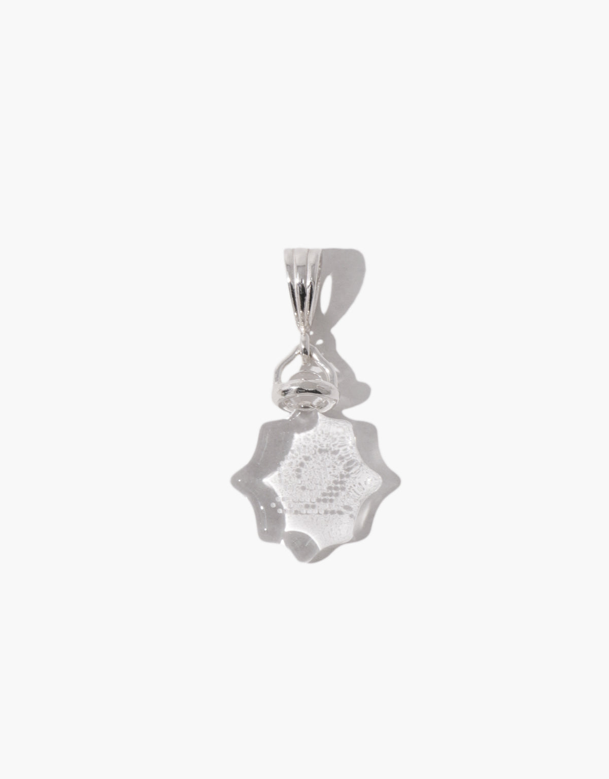 Detail of the Las Pendant | Scallop showing the engraving on a warm brown amber scalloped glass stone. Las Pendant | Scallop by CLED.