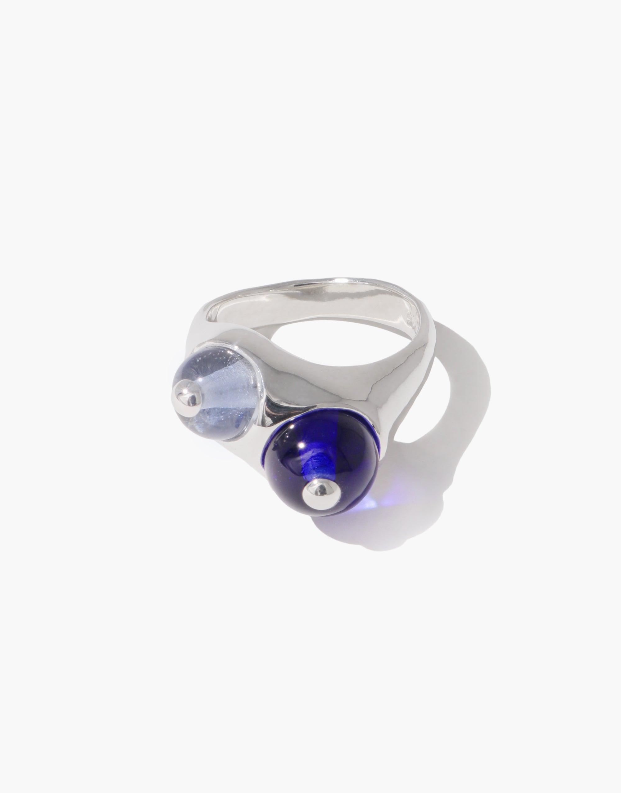 Elegant Pod Ring featuring two glass orbs, one clear and one deep blue, set in a sleek silver band. Inspired by organic legume shapes, this unique jewelry piece embodies nature's creativity and transformation. Pod Ring by CLED