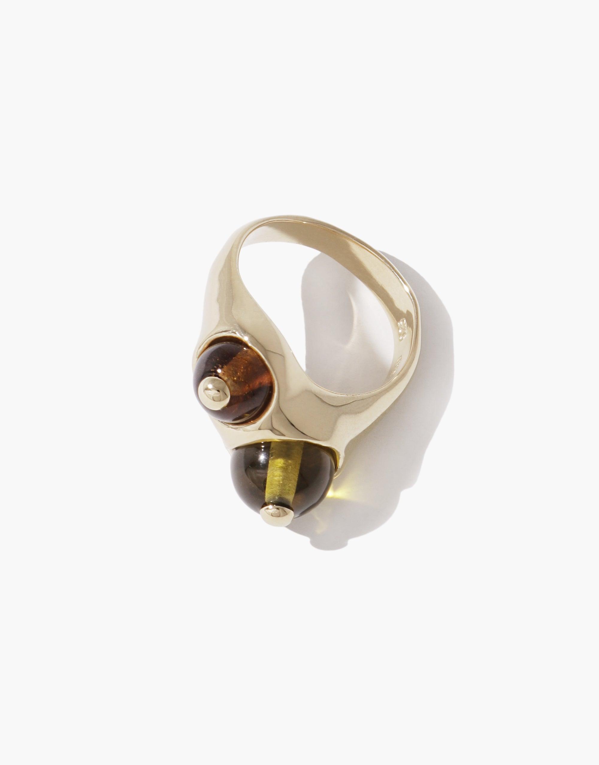 Elegant Pod Ring featuring a sleek gold-toned band with two contrasting spherical accents, one amber and one olive green, inspired by nature's organic shapes and patterns. Stylish and unique jewelry piece by CLED.
